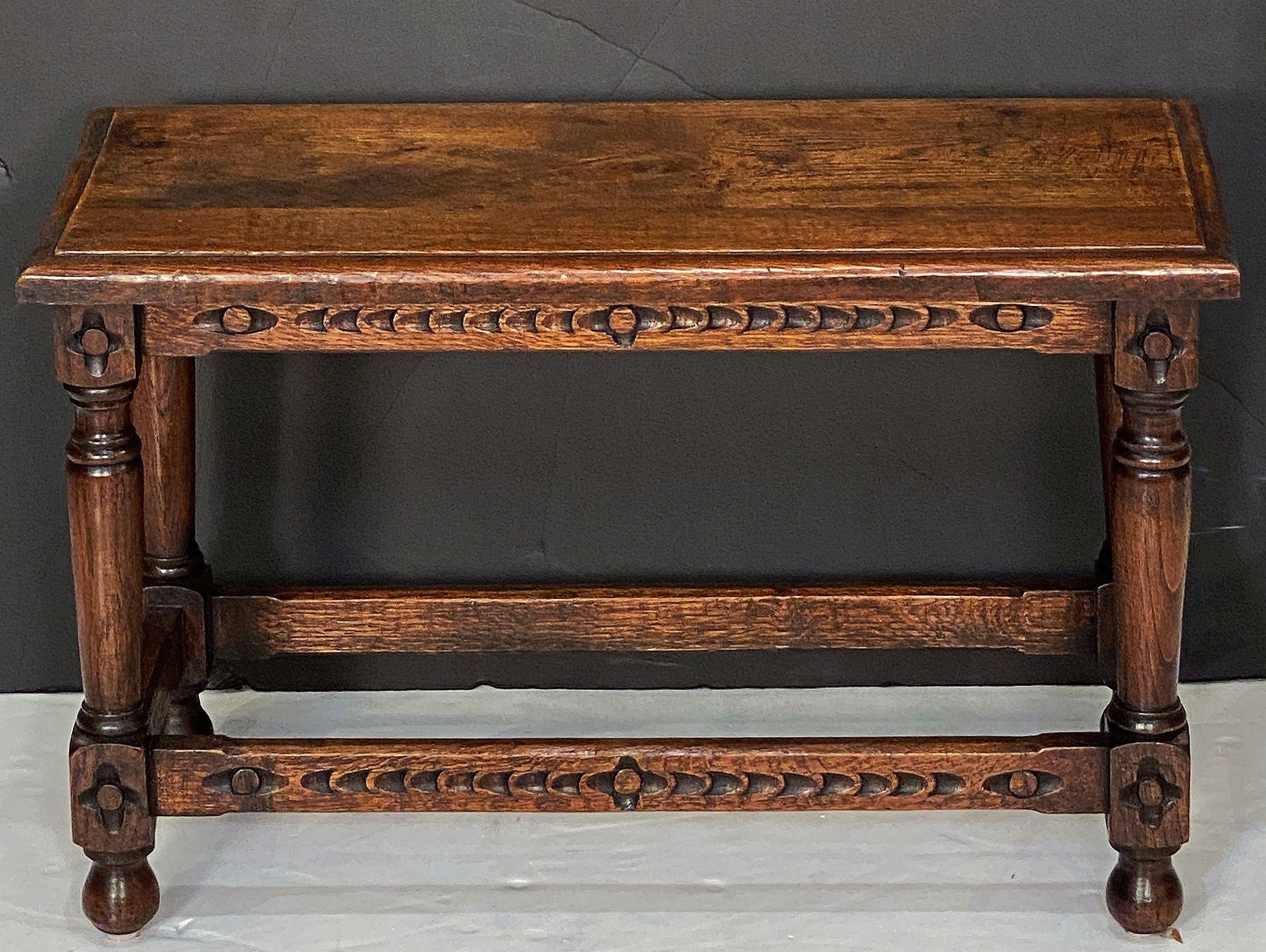 A fine English joint stool or seating bench of well patinated oak, featuring a rectangular top with moulded edge, set upon a stretcher base with a carved design on the frieze and four turned legs.