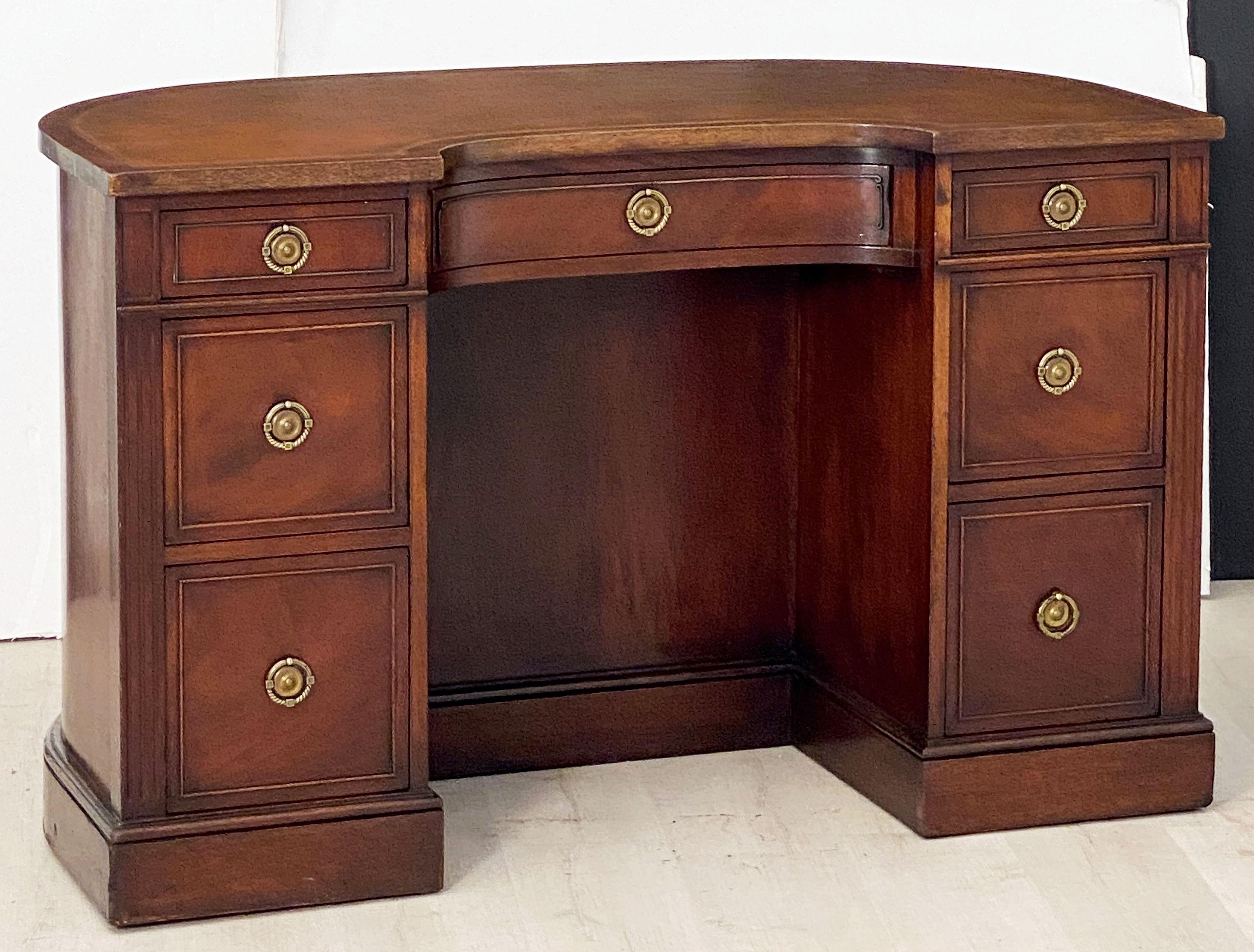A fine English kidney shaped kneehole writing desk from the Edwardian era, featuring a demi-lune top with original leather writing surface decorated with gold tooling in a Greek Key pattern, over a frieze of seven graduated mahogany-lined drawers