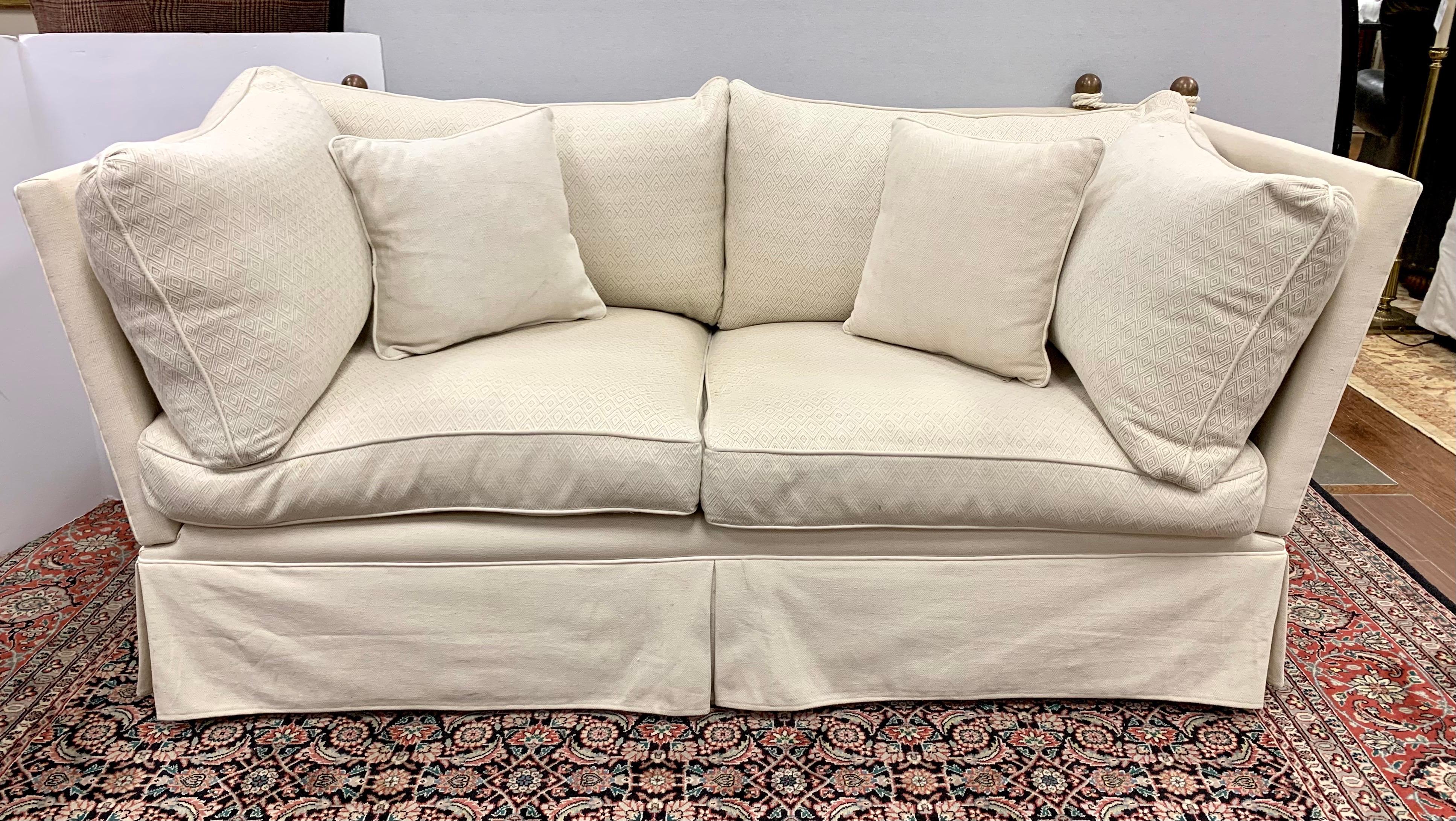 Elegant Knole loveseat with adjustable arms, deep seating and off-white upholstery. The cushions have a subtle diamond pattern and the backs and sides have a herringbone pattern. The traditional Knole sofa has drop arms and heavy decorative braid