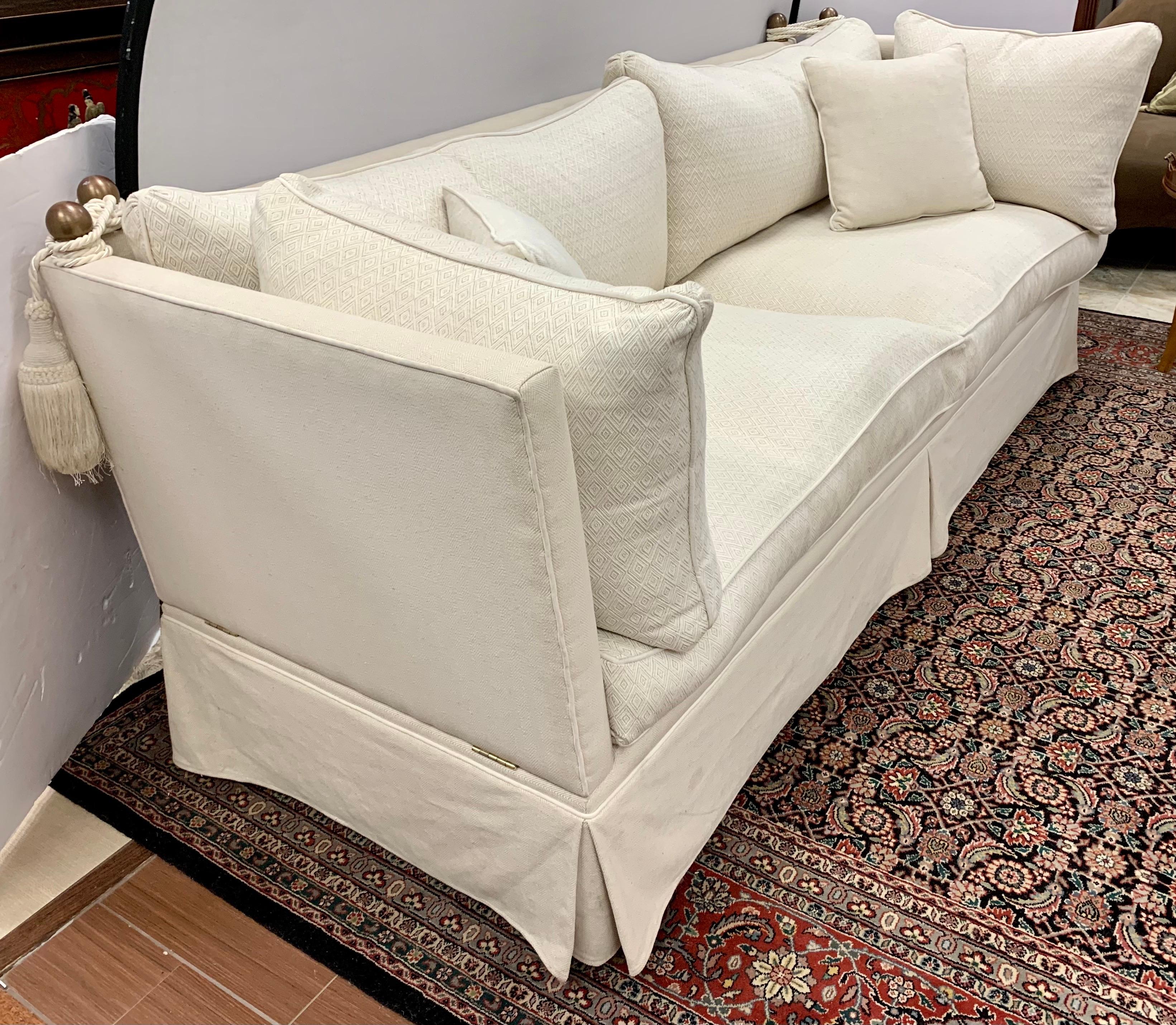 Elegant Knole sofa with adjustable arms, deep seating and off-white upholstery. The cushions have a subtle diamond pattern and the backs and sides have a herringbone pattern. The traditional Knole sofa has drop arms and heavy decorative braid tie