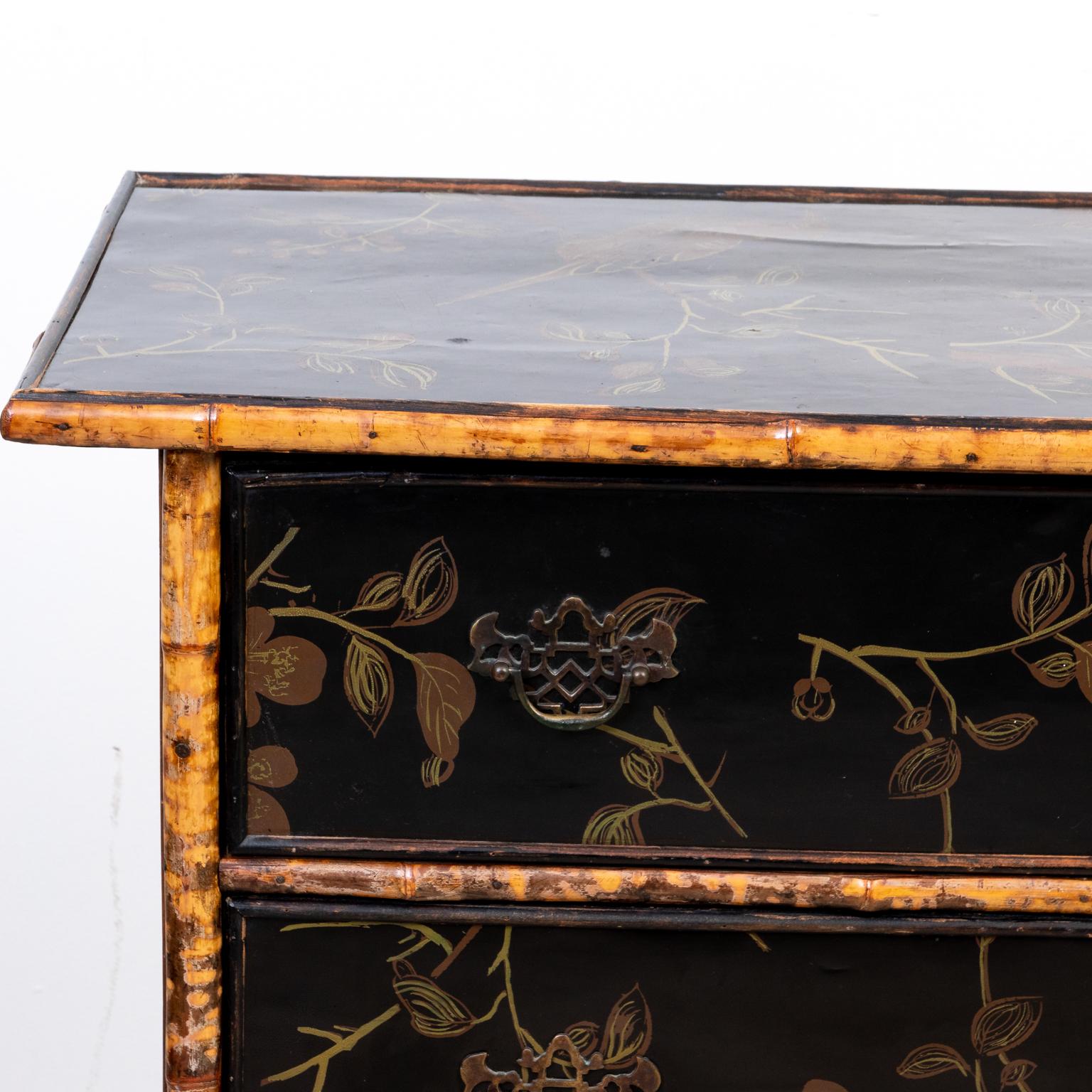 Circa 1870s English Chinoiserie style bamboo chest of drawers in a black lacquered finish with floral decoration on the drawer front and metal bat's wing escutcheon. Please note of wear consistent with age.
