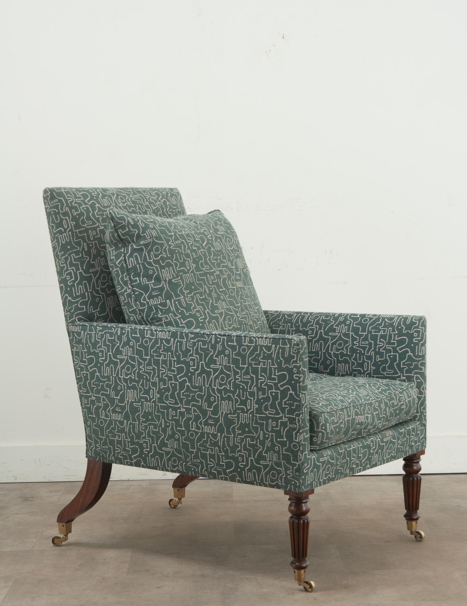 A single English Lancaster bergere chair from JAMB, London. This comfortable chair has a squared off back and arms supported by mahogany fluted and turned legs and splayed back legs, all on casters. This large chair has been recently upholstered in