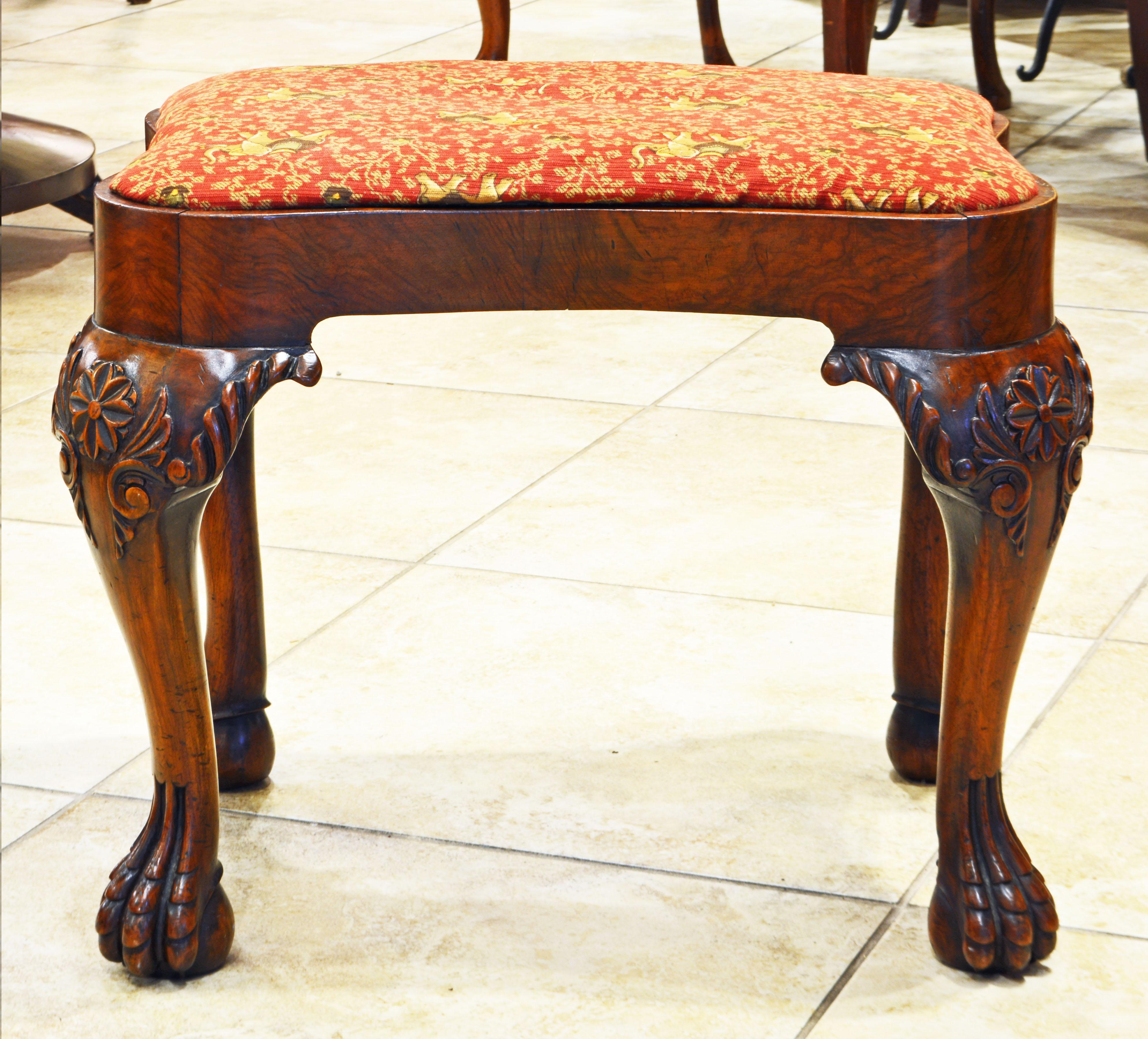 This late 18th or Early 19th century Chippendale mahogany bench features a shaped and covered detachable seat supported by four boldly carved cabriole legs ending in carved claw and ball feet.