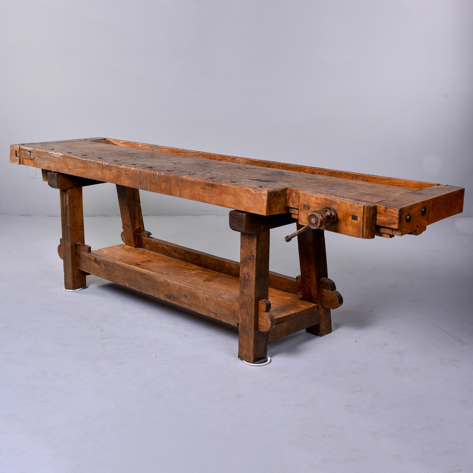 This circa 1880s work bench table is made of heavy oak and was found in England.  The clamp is still present, along with a work trough on the table top. Plenty of honest wear and patina to wood surfaces. Mortis and tenon construction at the base and