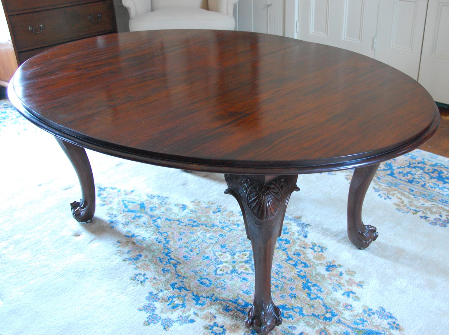 English Chippendale style solid mahogany banquet table with four leaves, carved cabriole legs and paw feet, continuous screw mechanism with crank for easily expanding or contracting the table, circa 1890-1900. Top constructed in part from 18th