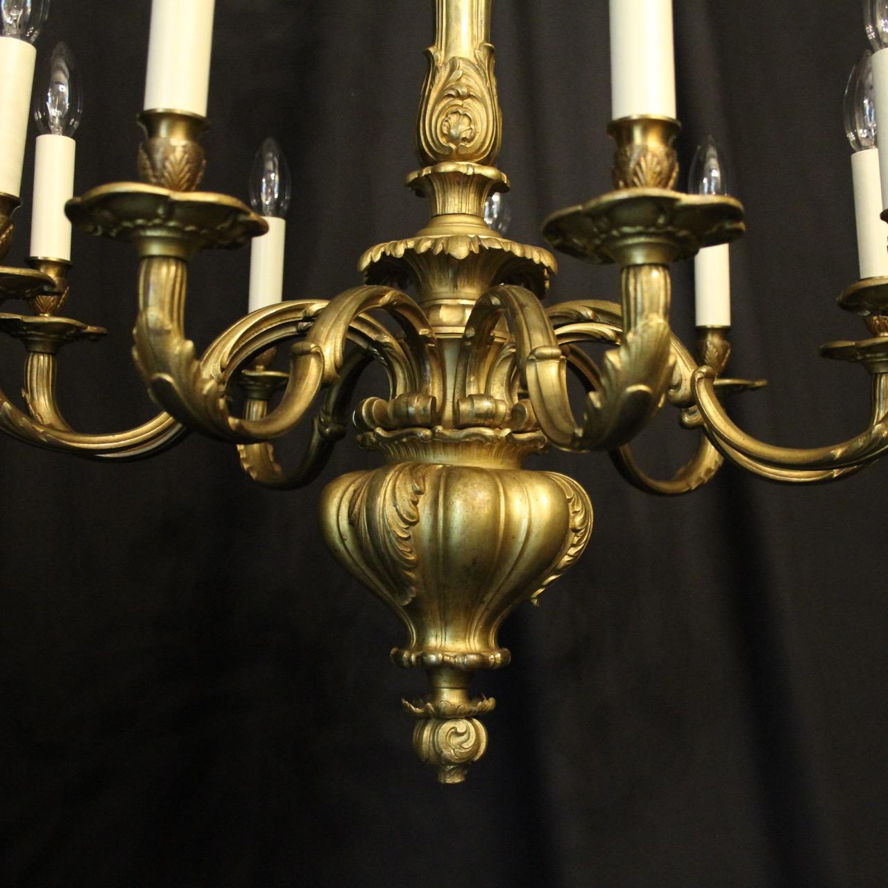 A large English gilded cast bronze eight-light antique chandelier, the reeded ornate leaf scrolling arms with sectional leaf bobeche drip pans and anthemion candle sconces, issuing from a tapering central column with three crisply cast cherub heads