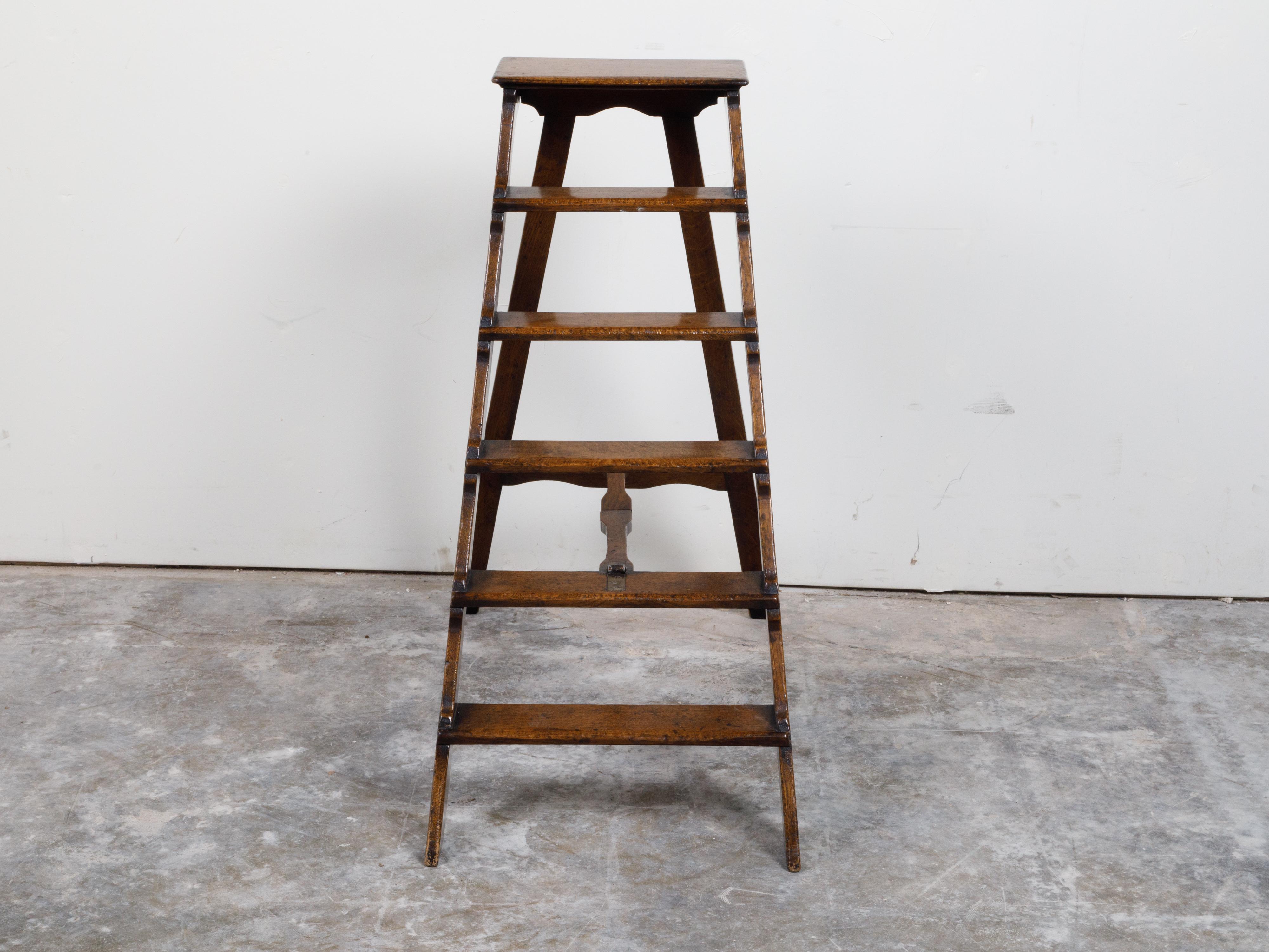 An English oak step ladder from the late 19th century, with brown patina. Created in England during the last decade of the 19th century, this oak ladder features five steps connected to the back splaying support through a two-part stretcher.