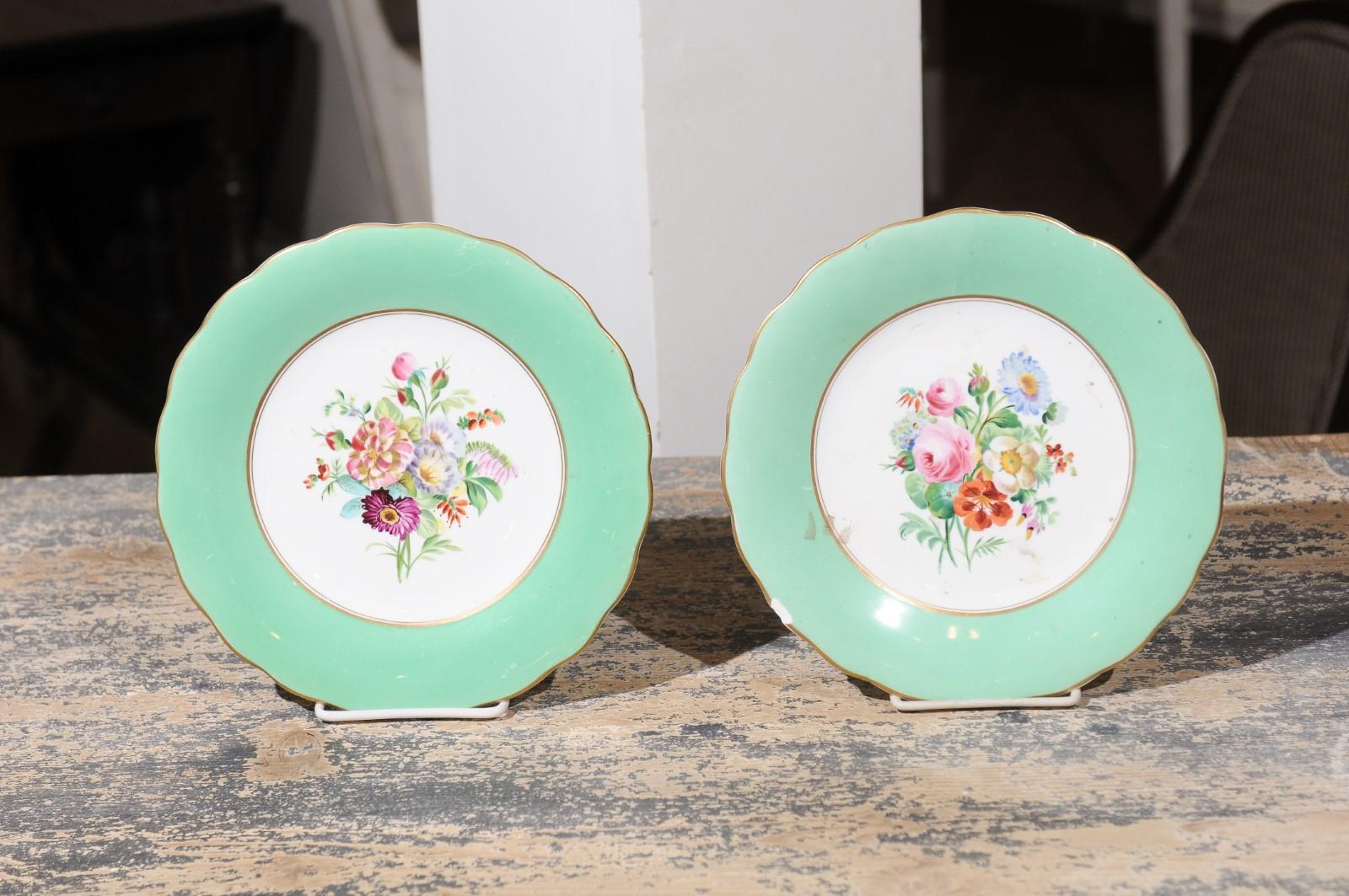 A pair of English Victorian floral plates from the late 19th century, with green and gold trim. Born in England during the 19th century, each of this pair of plates features a stunning bouquet of colorful flowers including pink roses and daisies.