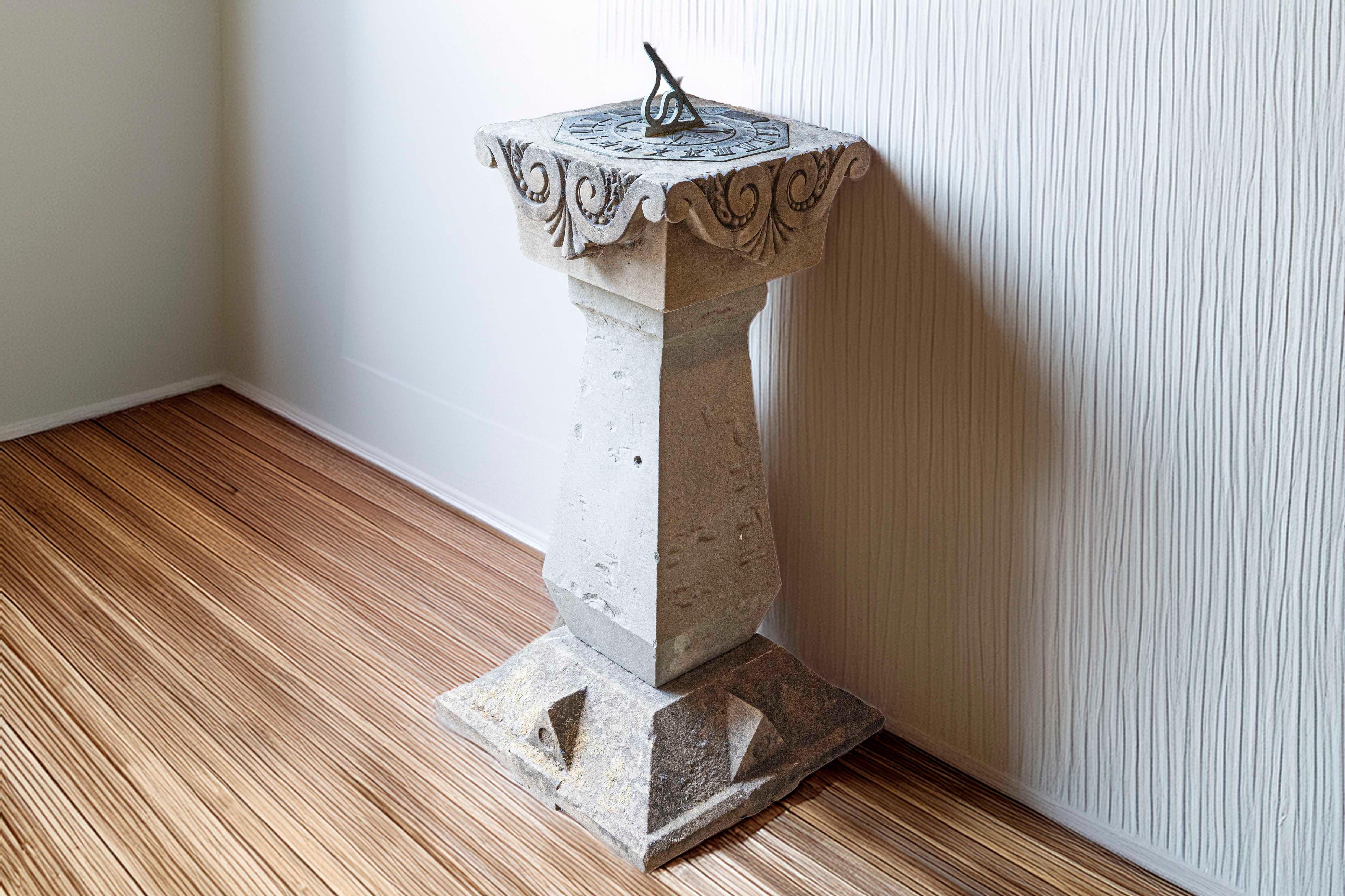 An English sundial from the late 19th century, with carved limestone and bronze top. This English sundial features an obelisk-shaped base, raised on a pyramidal plinth, with cut-off top. Each side is adorned with triangular motifs reminiscent of