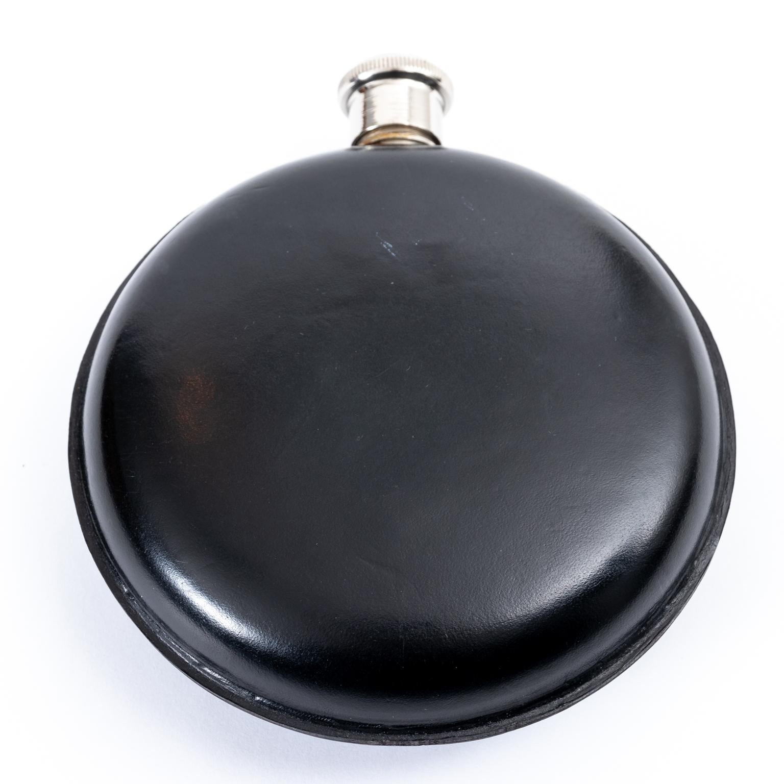 English round leather flask with fitted center cup, circa mid-20th century. Made in England. Please note of wear consistent with age.

 