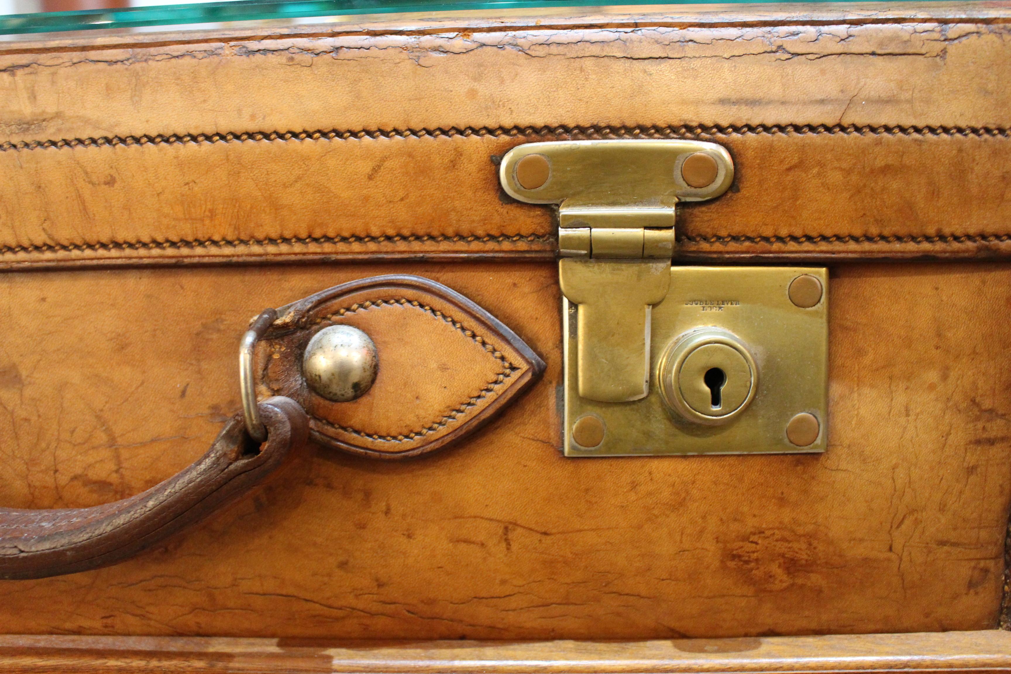 English leather suitcase on stand with glass top.