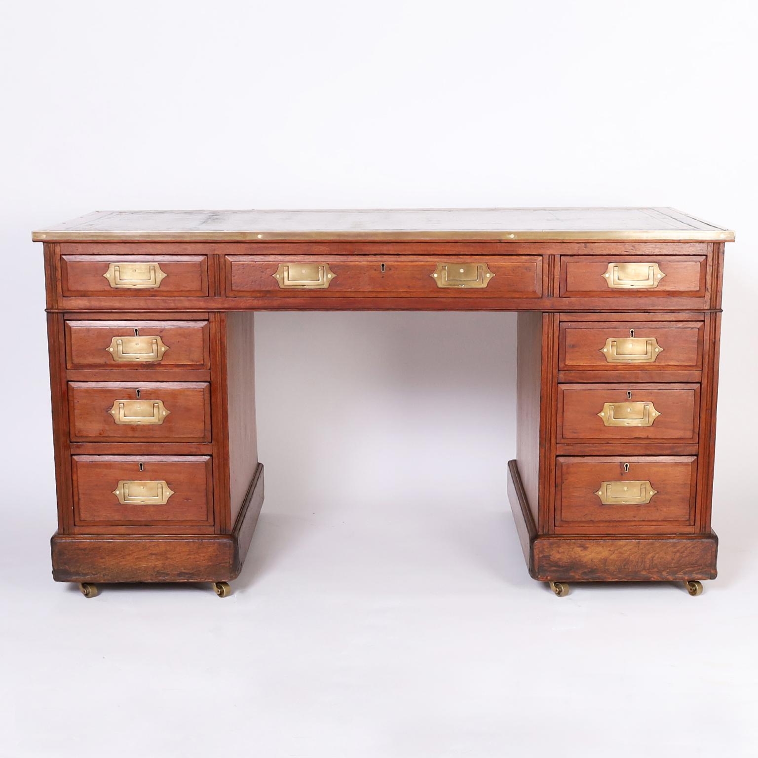 Handsome 19th century English campaign desk featuring the original tooled green leather top, campaign brass hardware, two pedestals and a case with nine paneled drawers and block feet. 

Kneehole measures H: 23.5 W: 25