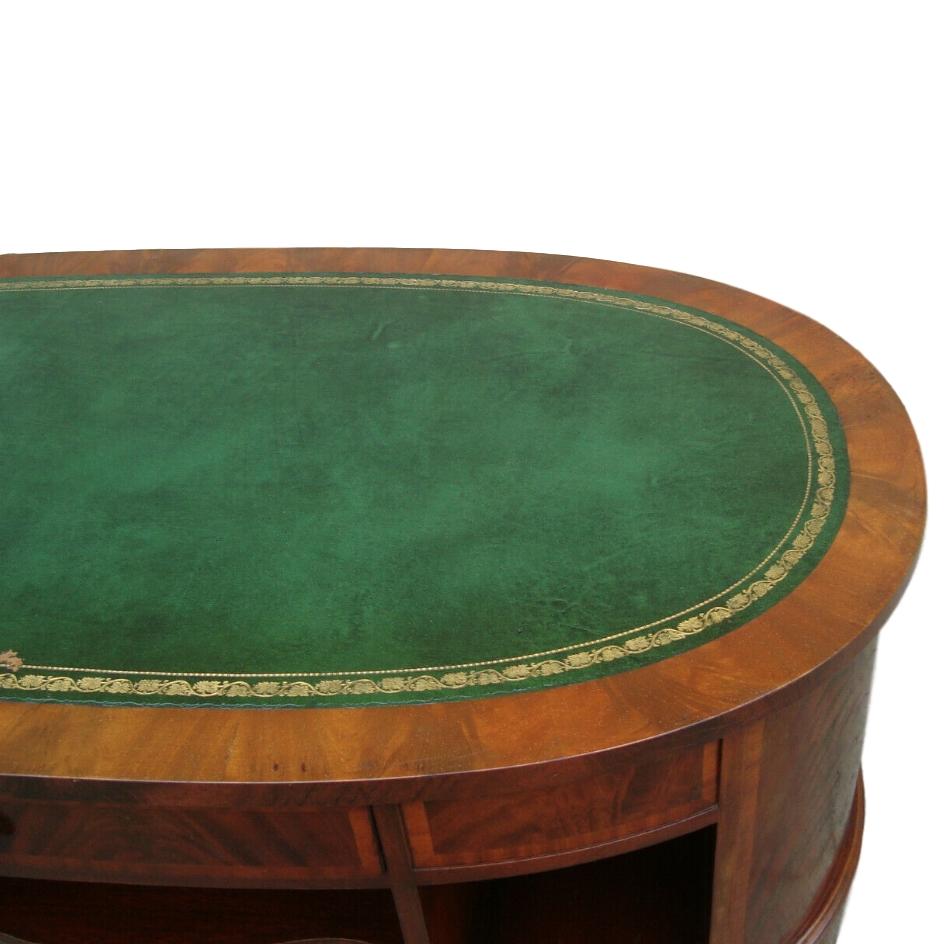 English oval coffee table with embossed leather top, side and central shelves and drawers on base, circa 1940s.

Measurements:
Length 50