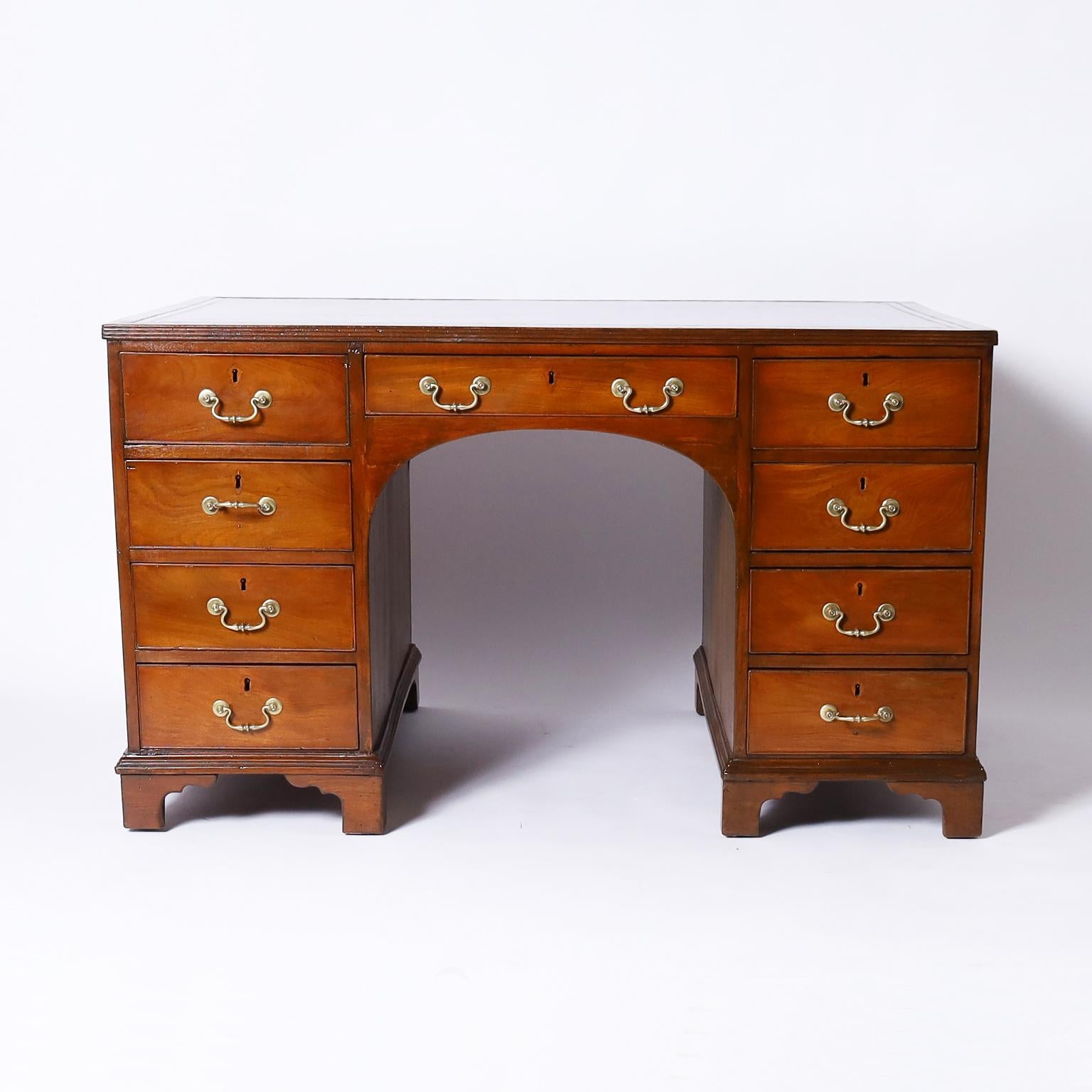 19th century English partners desk hand crafted in mahogany with a tooled leather top and brass hardware, one side with nine drawers, the other side with three drawers and two cabinets set on ogee bracket feet.