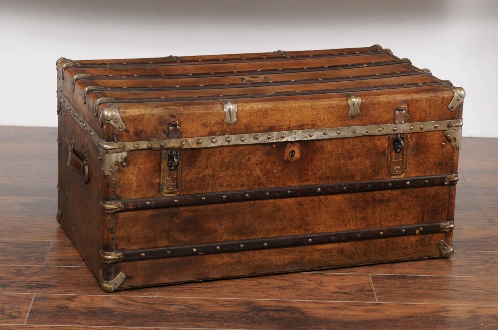 An English leather trunk, zinc lined with lateral handles from the late 19th century. This English leather trunk features a rectangular top, accented with straps and brass details, that lifts up to reveal a zinc lined interior, offering great