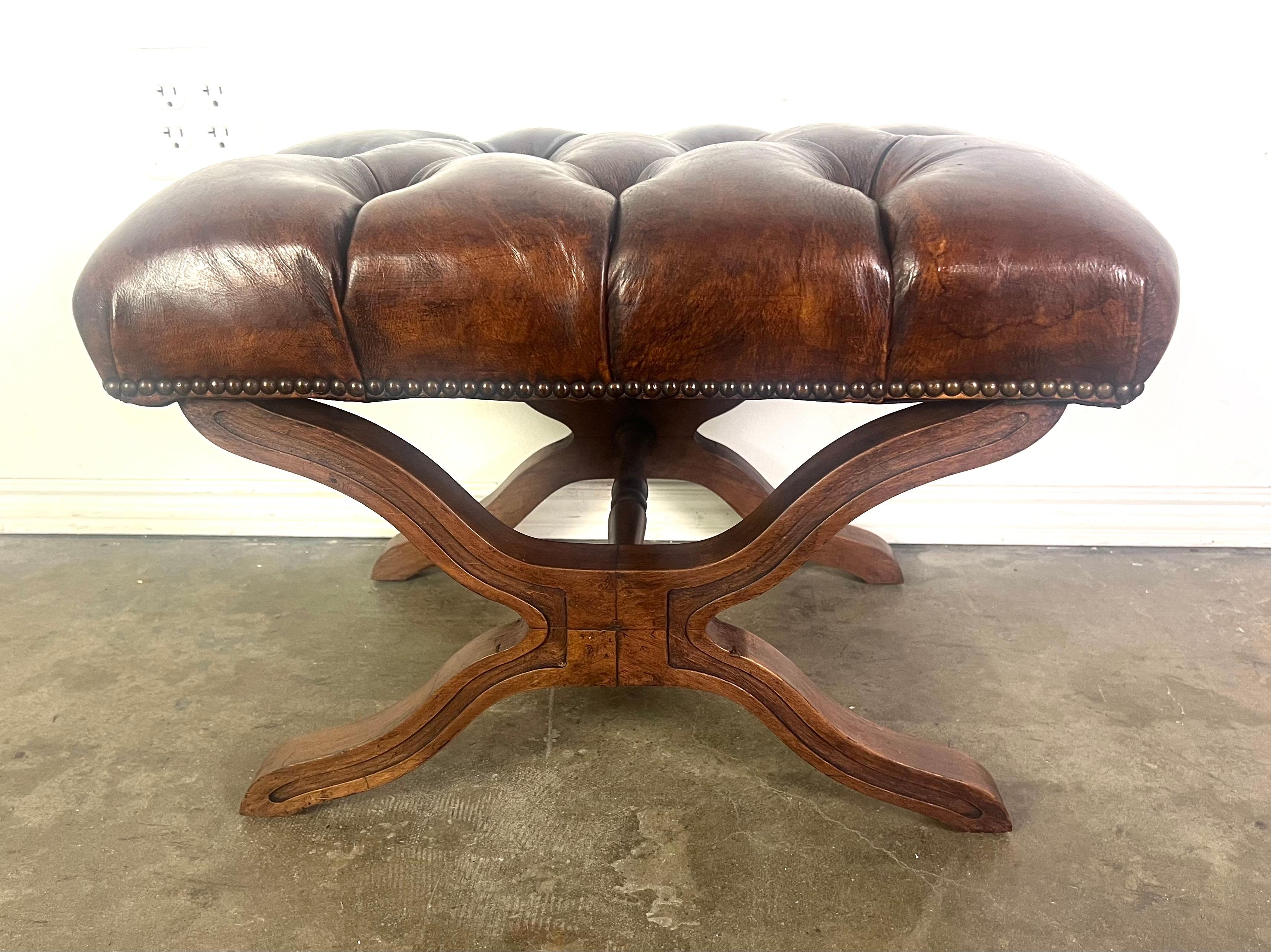 Banquette anglaise en cuir tufté de couleur marron foncé.  Le coussin est orné d'une garniture en tête de clou sur les bords.  La base du banc est fabriquée en bois avec un design élégamment incurvé, formant un 