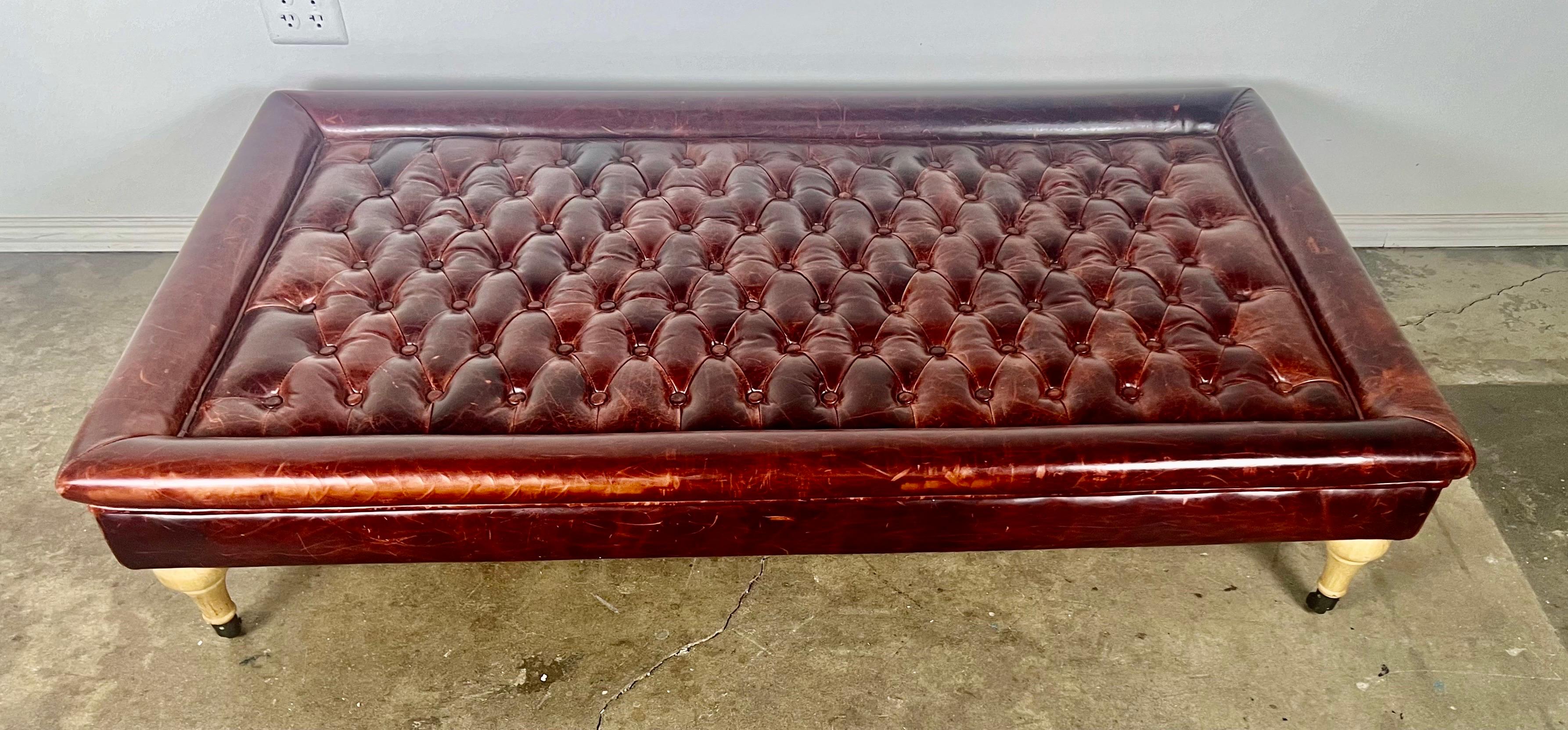 Monumental scale Chesterfield style leather tufted ottoman.  It stands  on four oak legs with original casters.  The leather is in great condition and is beautifully distressed, adding character and warmth to the unique piece.