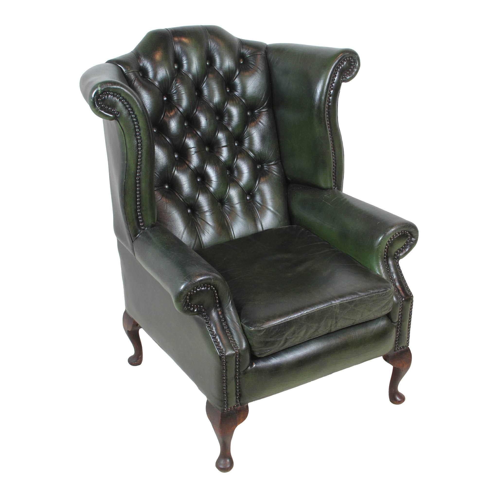 Upholstered in green leather with a tufted back and nail-head trim, this regal wingback chair is both stately and comfortable. It is raised on cabriole legs, which terminate in pad feet.