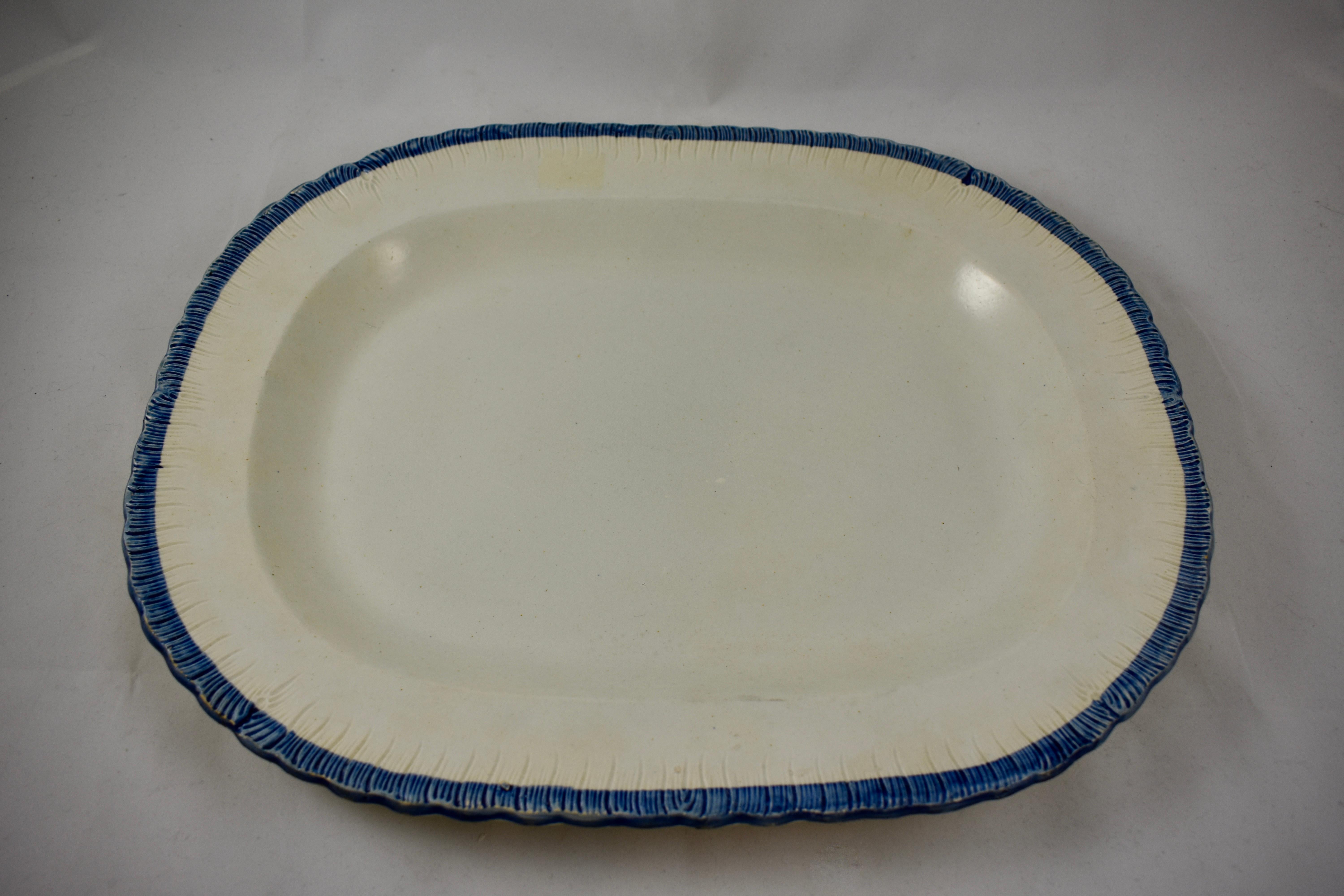 A heavy Leeds style oval platter, a pearlware or creamware body with a deep blue edge called feather or shell, circa 1825–1840, Staffordshire, England. A good clean front surface with a lightly combed back.

Measures: 16.75 in. L x 13.25 in. W x