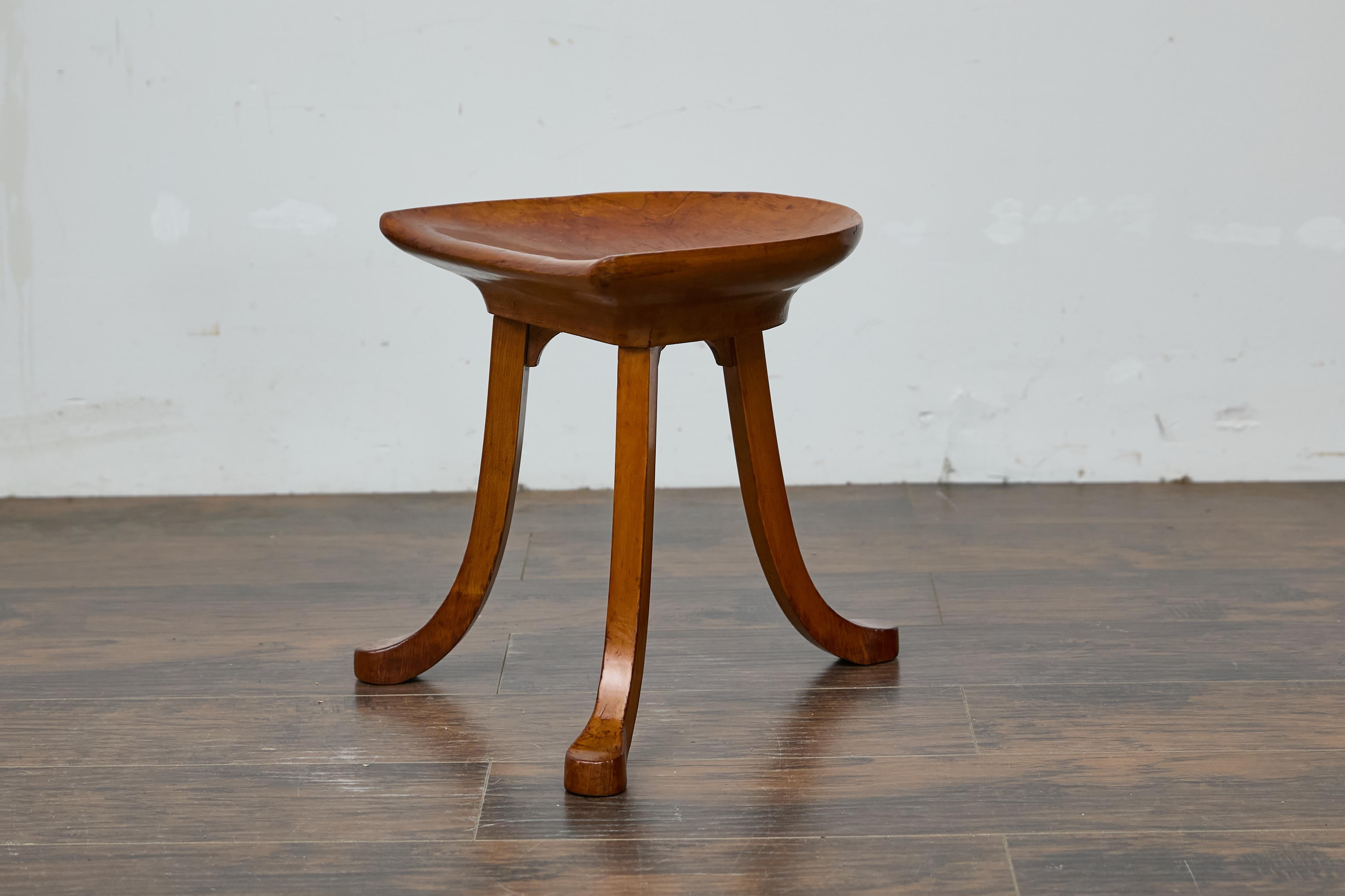 Uno sgabello inglese Liberty & Co. in noce di fine secolo con base a treppiede. Il sedile in legno curvo poggia su tre gambe delicatamente curve. Questo sgabello inglese in noce Thebes di Liberty & Co. di inizio secolo cattura l'essenza del design