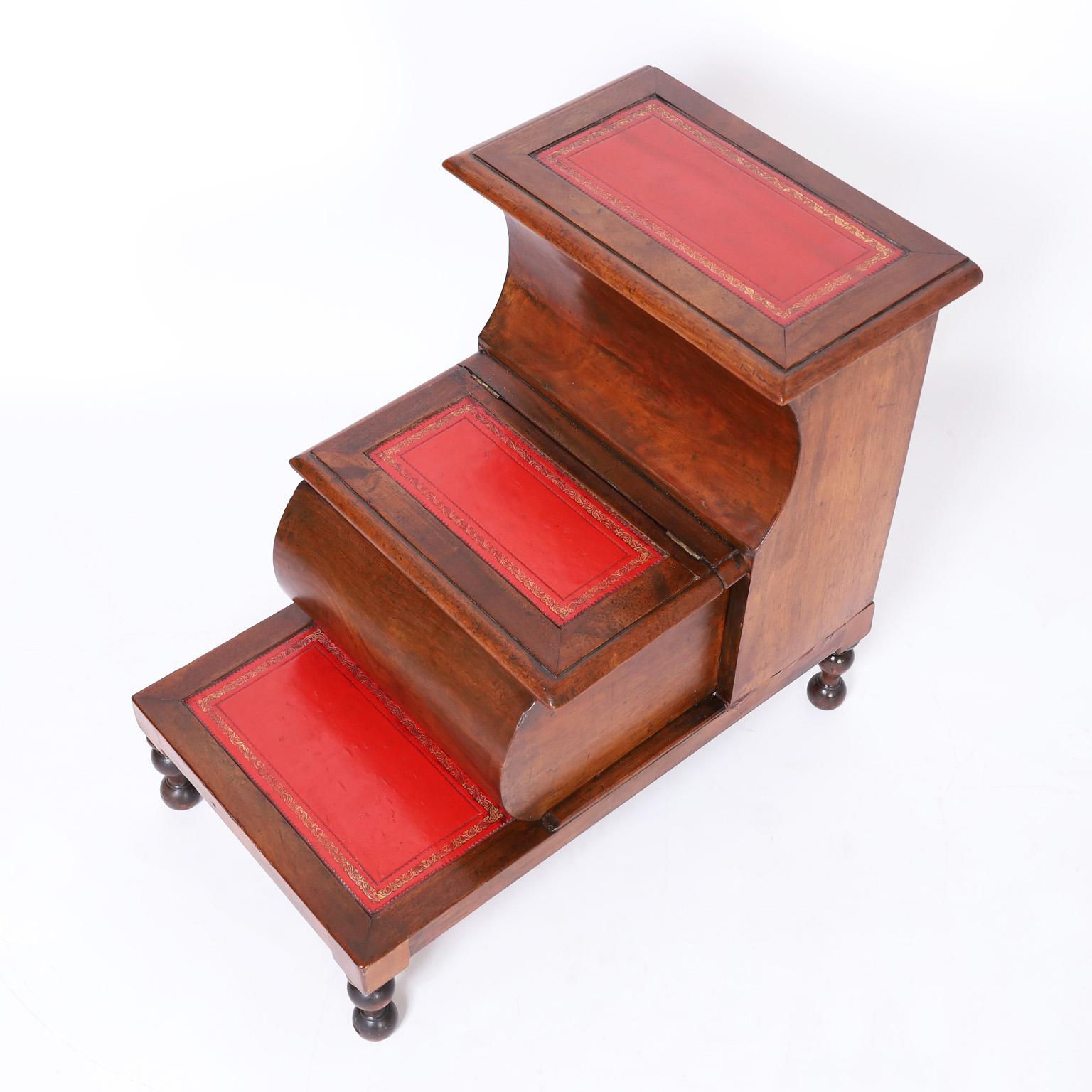 19th Century English library stairs crafted in mahogany with three tooled red leather steps, two flip top storage compartments, a pull out drawer and turned legs.
