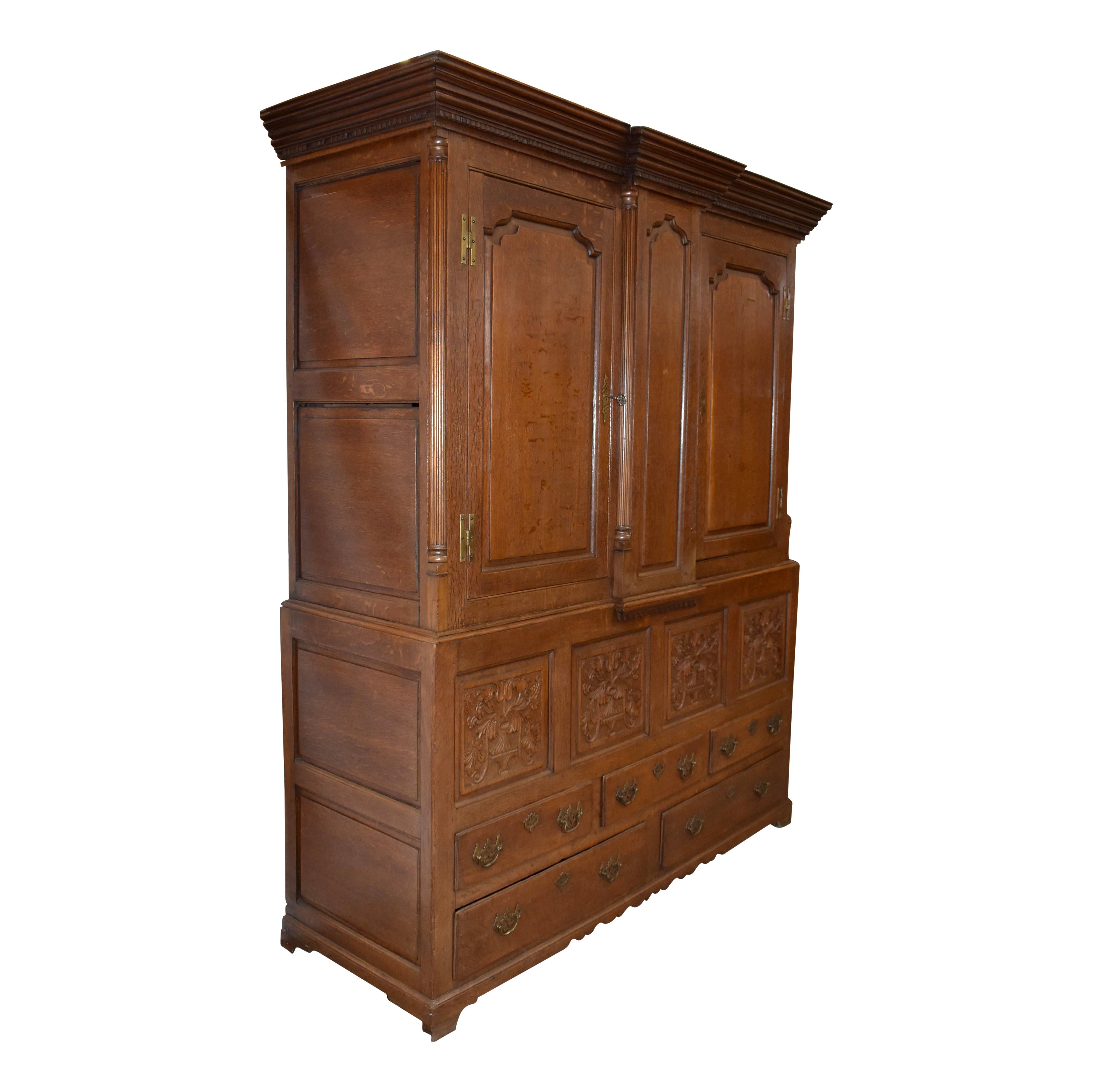 Generous storage abounds in this beautiful linen press cabinet from England. Featuring solid oak, double bodied construction, the top piece of the cabinet showcases a breakfront design and a molded cornice with dentil trim. The raised panel doors