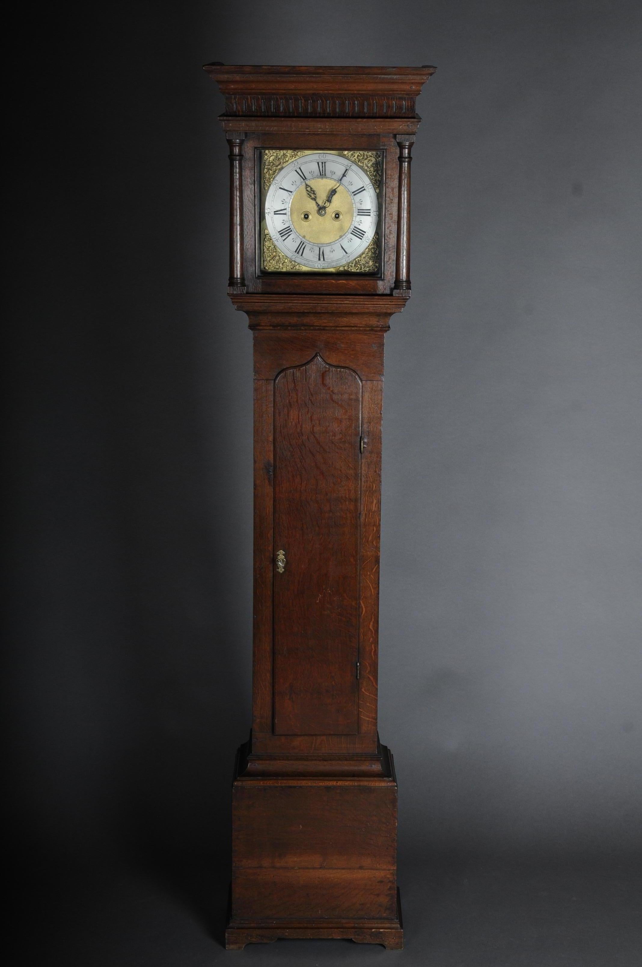 English longcase clock/grandfather clock George III circa 1800

Simple, single-door oak case. Head with glazed front, half columns and profiled gable. Brass dial with rocailles and a silver-plated wreath with black, Roman and Arabic numerals,
