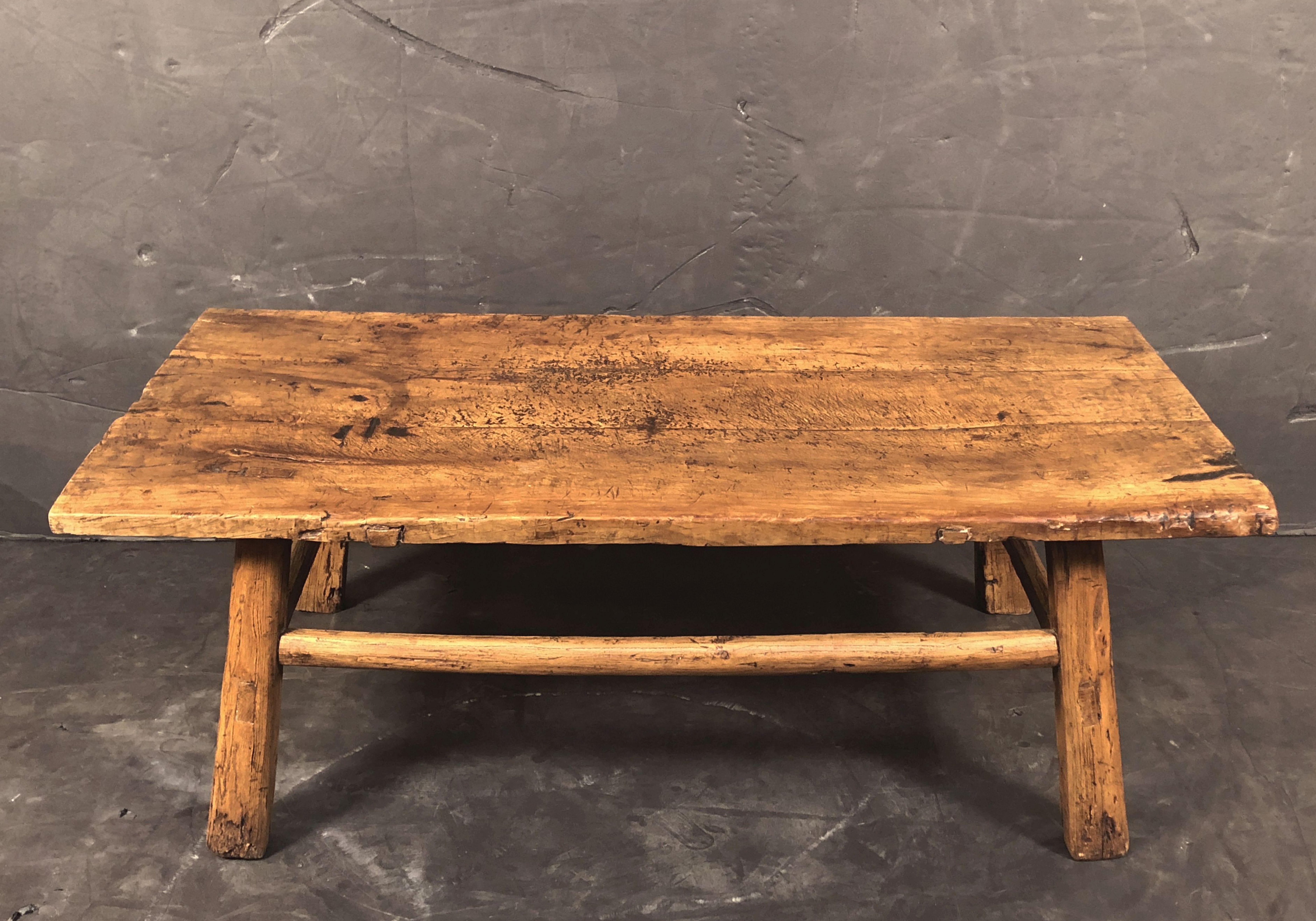 A large English cocktail or low table of fruitwood featuring a handsome rectangular plank top set upon a rustic stretcher frame of four pegged and joined legs.

Perfect for use as a coffee table.