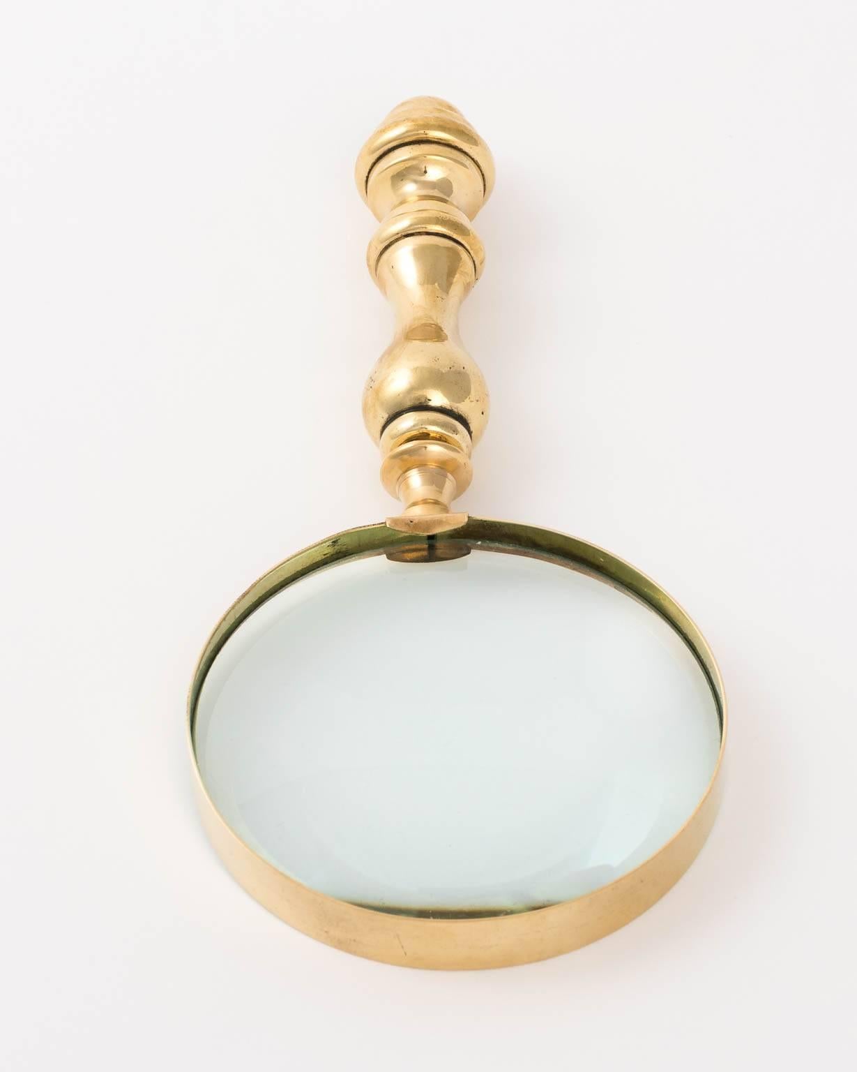 English brass magnifying glass in a polished finish with a vase-and-ring styled handle, circa 1890.
 