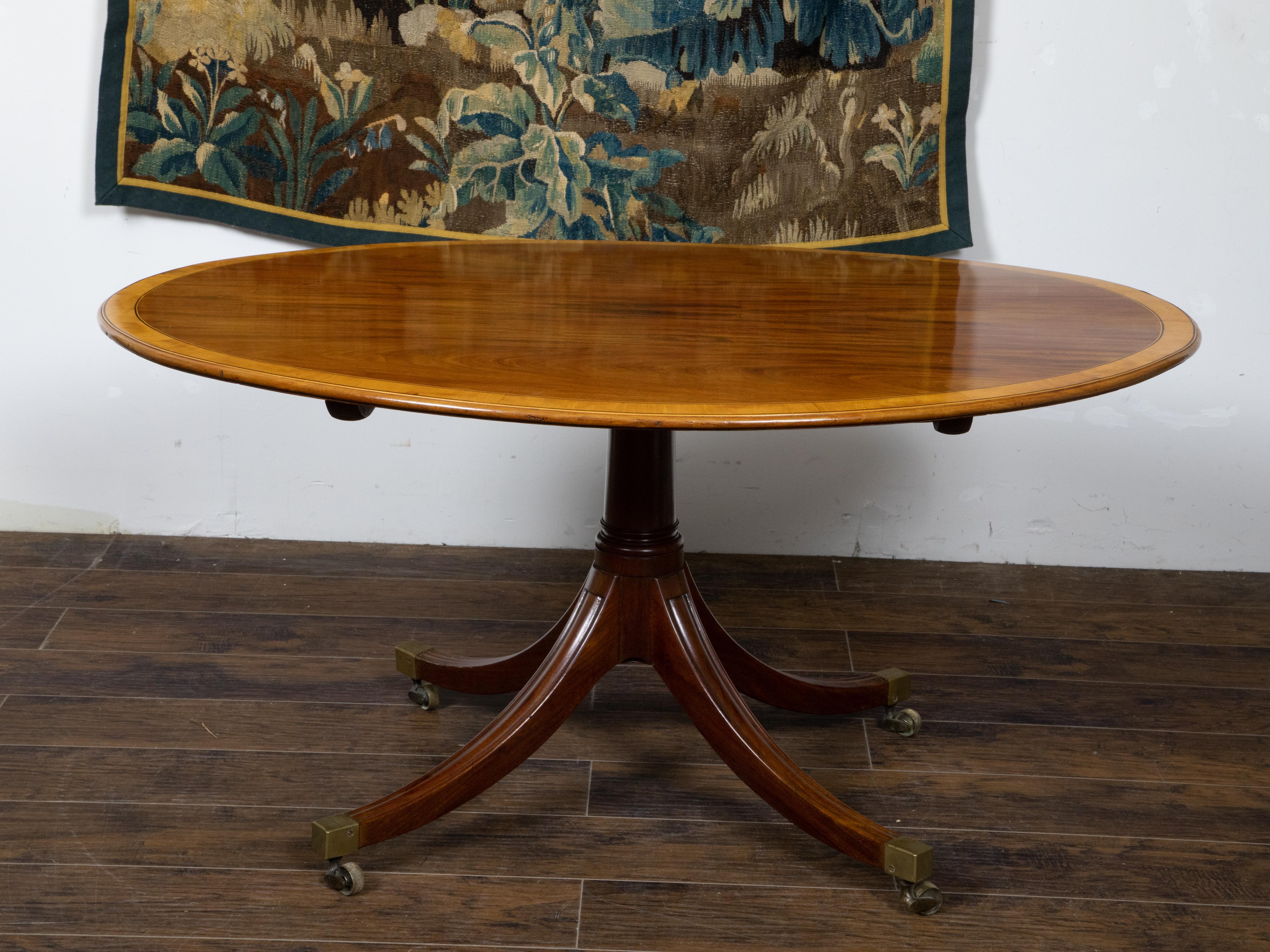 Cross-Banded English Mahogany 1840s Oval Top Pedestal Table with Quadripod Base and Casters For Sale