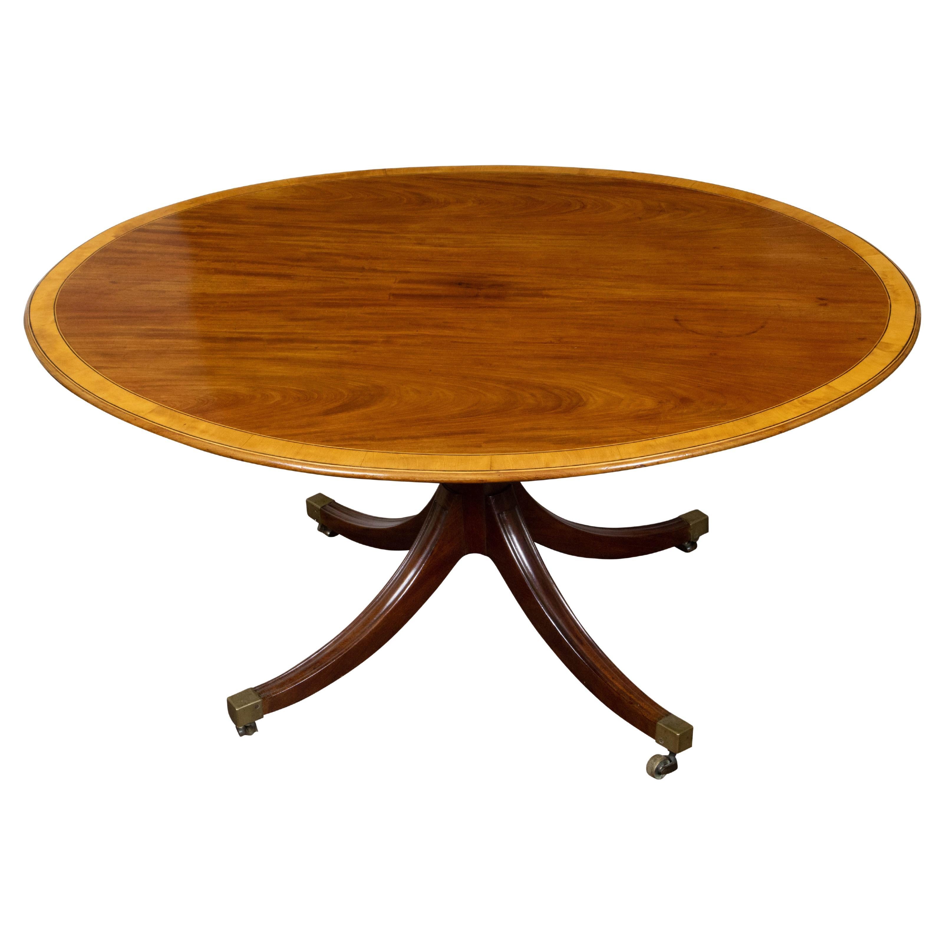 Mesa de pedestal con tablero ovalado de caoba inglesa de la década de 1840, con base cuadrípode y ruedas