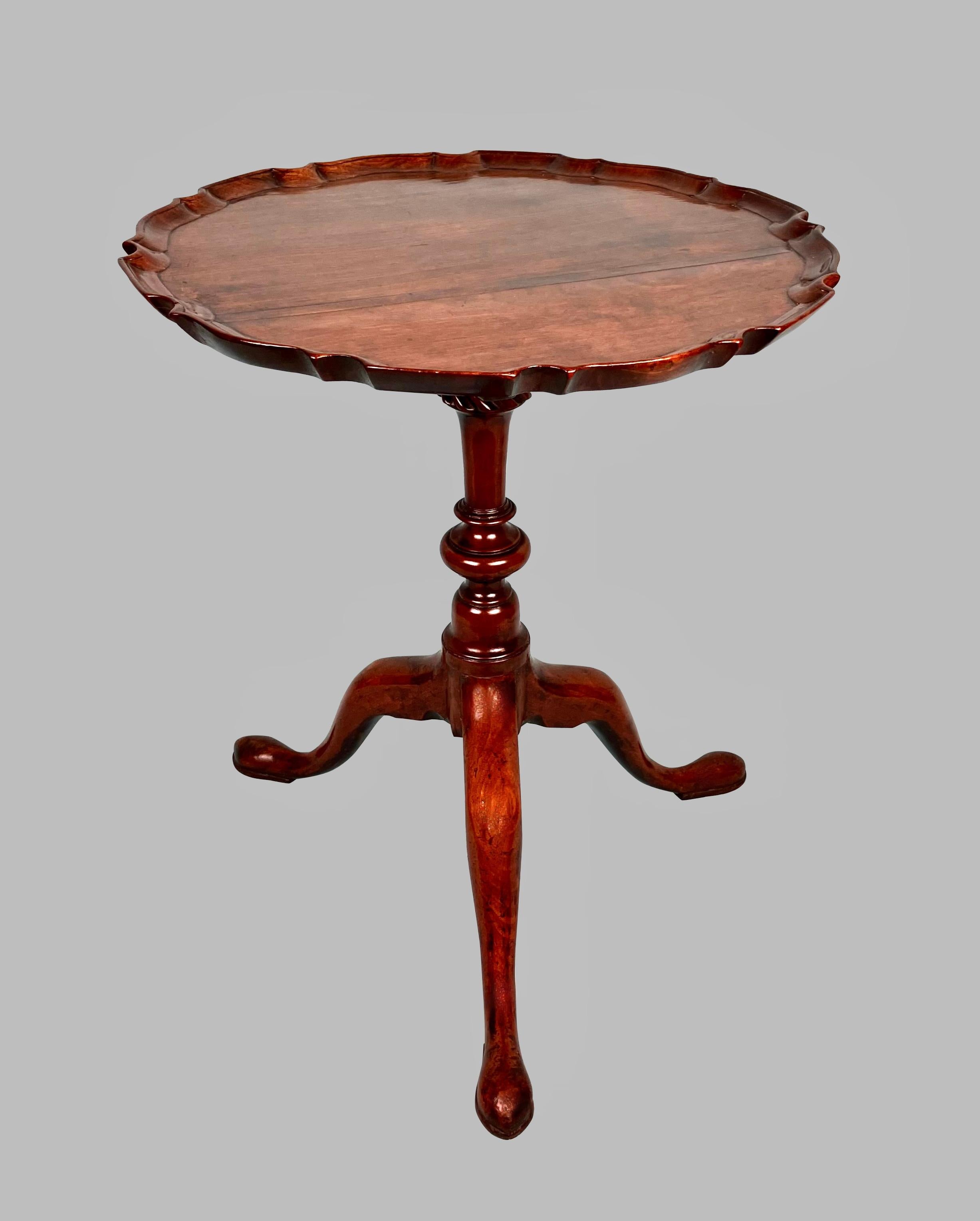 A charming small English mahogany Chippendale period occasional table with a well carved pie crust edge supported on a well-turned baluster column with a fluted top supported on a tripod base with pad feet. Attractive figure to the top. Old repairs.