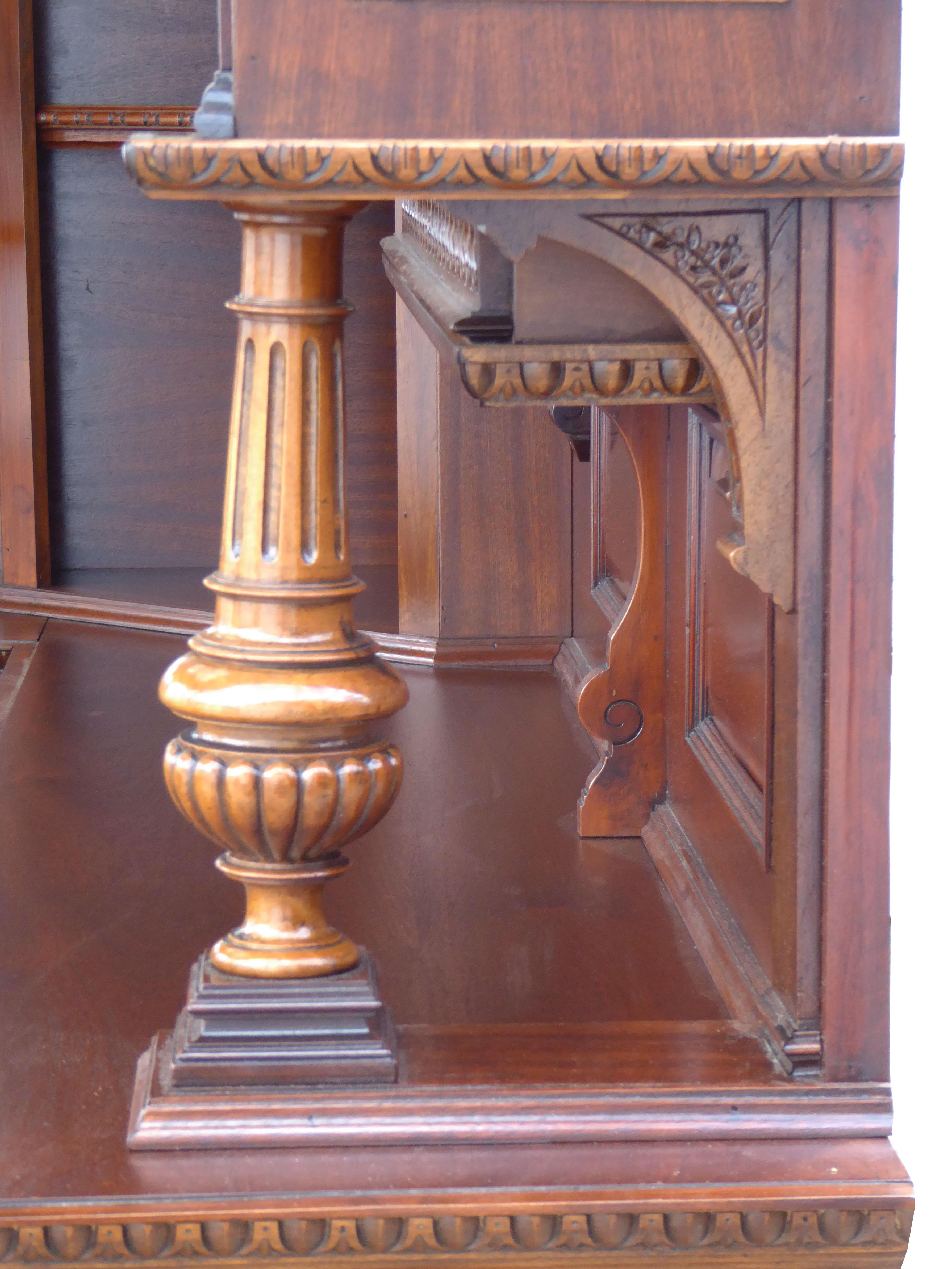 For sale is a good quality English mahogany and walnut carved canted corner bar. The bar has a decorative canopy with an antique stained glass ceiling, with arched edges decorated with carved corbels. At the front there are two columns to support