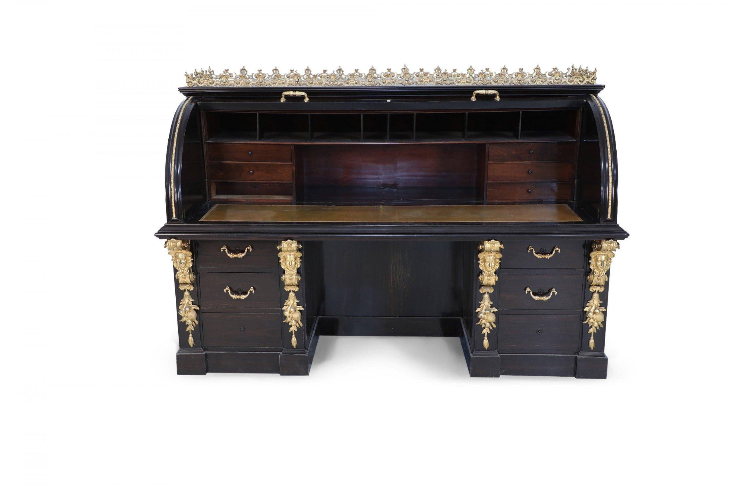English Victorian style mahogany roll top desk that opens to reveal drawers, letter holders, and a gold embossed leather desk surface, with a gilt bronze filigree gallery top, under two columns of drawers, each with a gilt bronze pulls flanked by