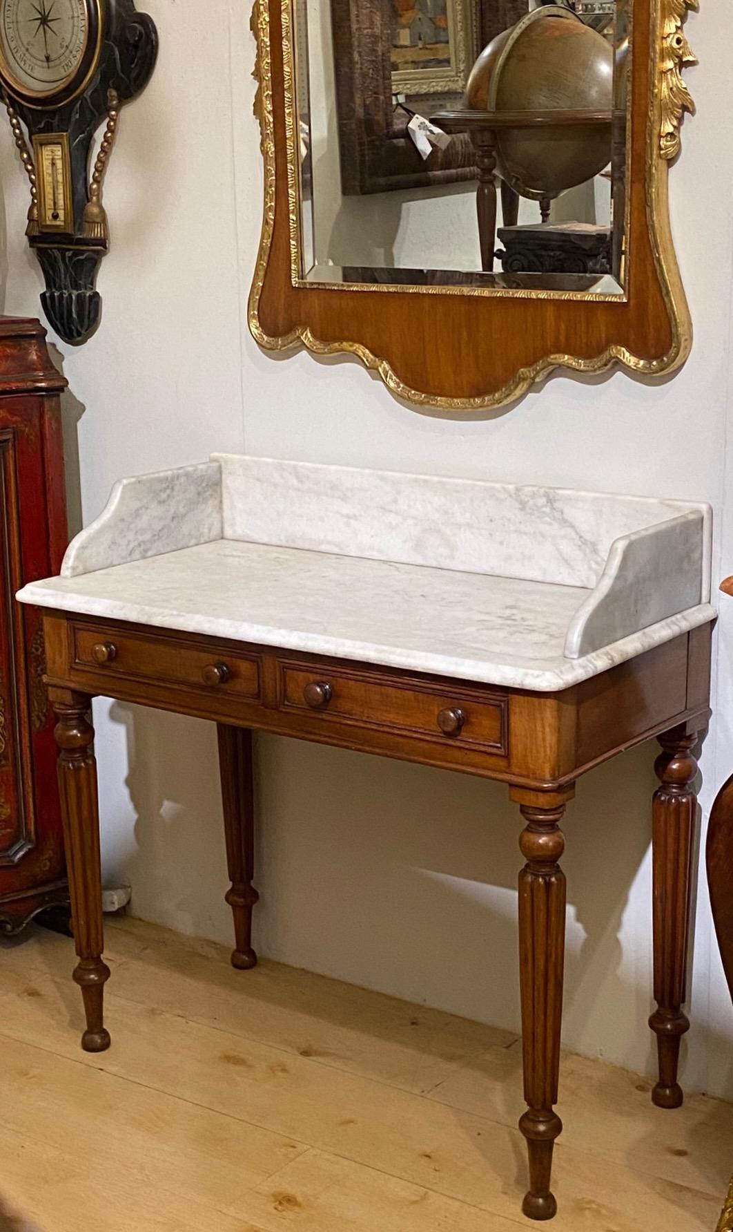This mahogany wash stand or dressing table features a traditional elegant design with a marble top over two drawers.
George IV period, early 19th century, England.
In excellent antique condition.