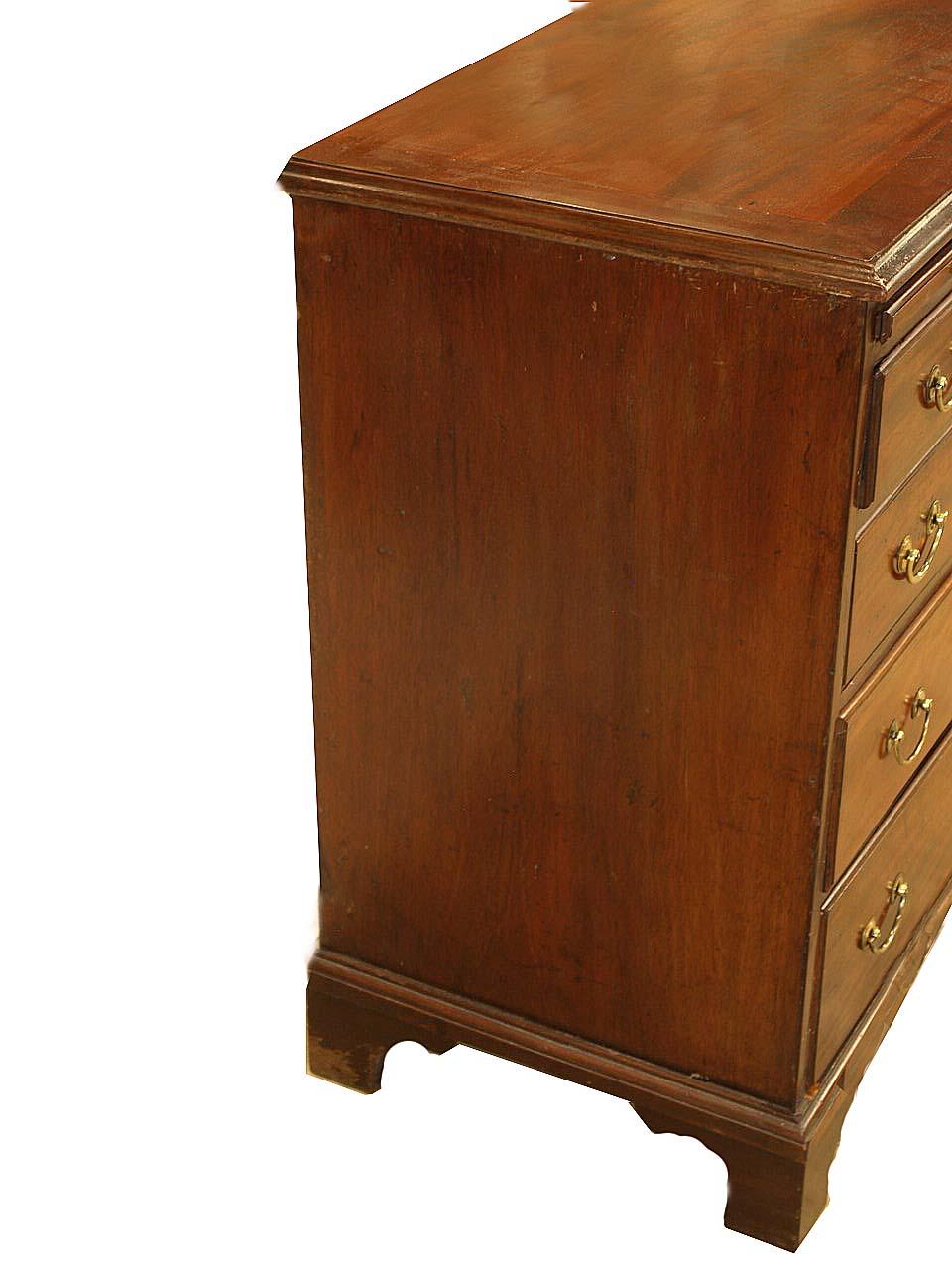 English mahogany bachelor's chest, with cross banded top, the four graduated drawers with overlapping molding are below the pull out brushing slide; the secondary wood is oak. The brass pulls are antique but not original; the chest rests on bracket
