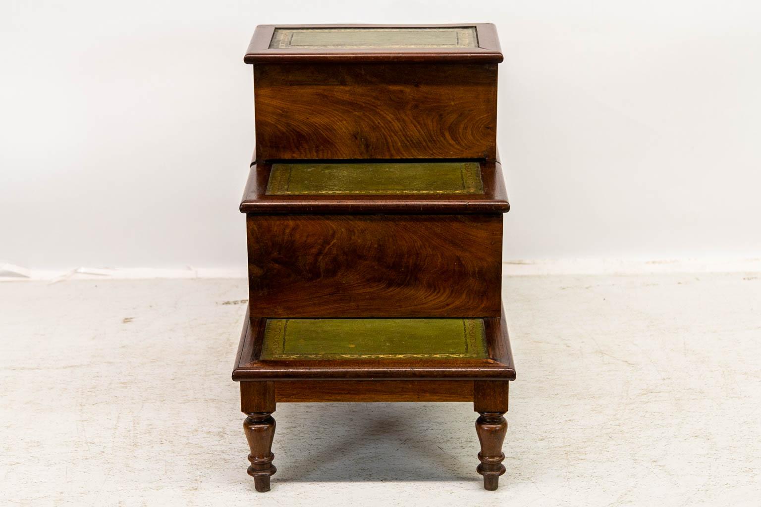 The potty compartment of this commode retains its original turned wooden lid. The earthenware potty is missing. Each step has later replaced gold and blind tooled leather. The center step pulls out, and the top lifts up to expose the commode