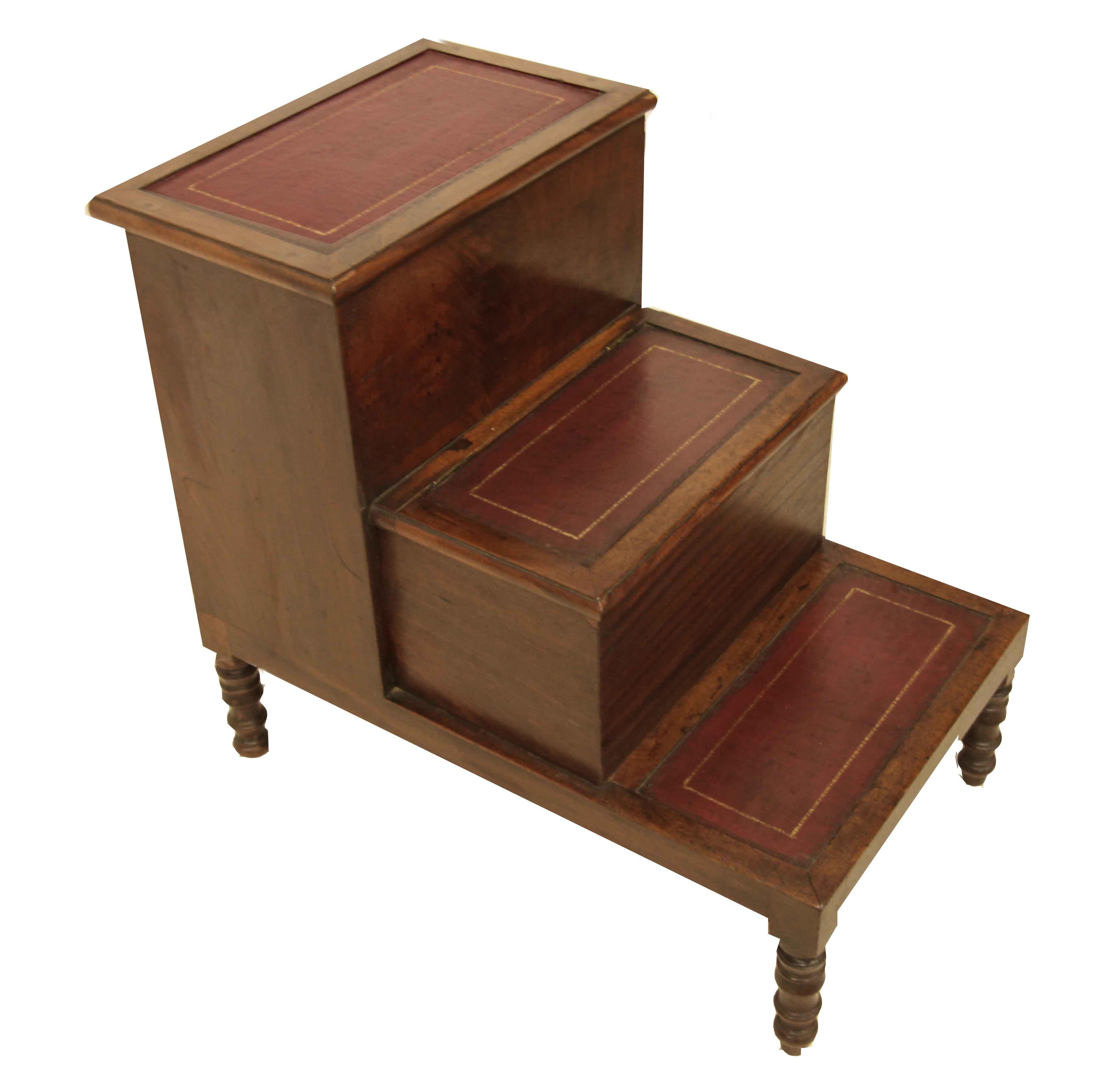 English mahogany bed steps, the three steps have tooled leather insets ( not original ) , the top step lifts up to reveal open storage, the middle step pulls out and originally had a porcelain potty.  The steps rest on turned feet. 