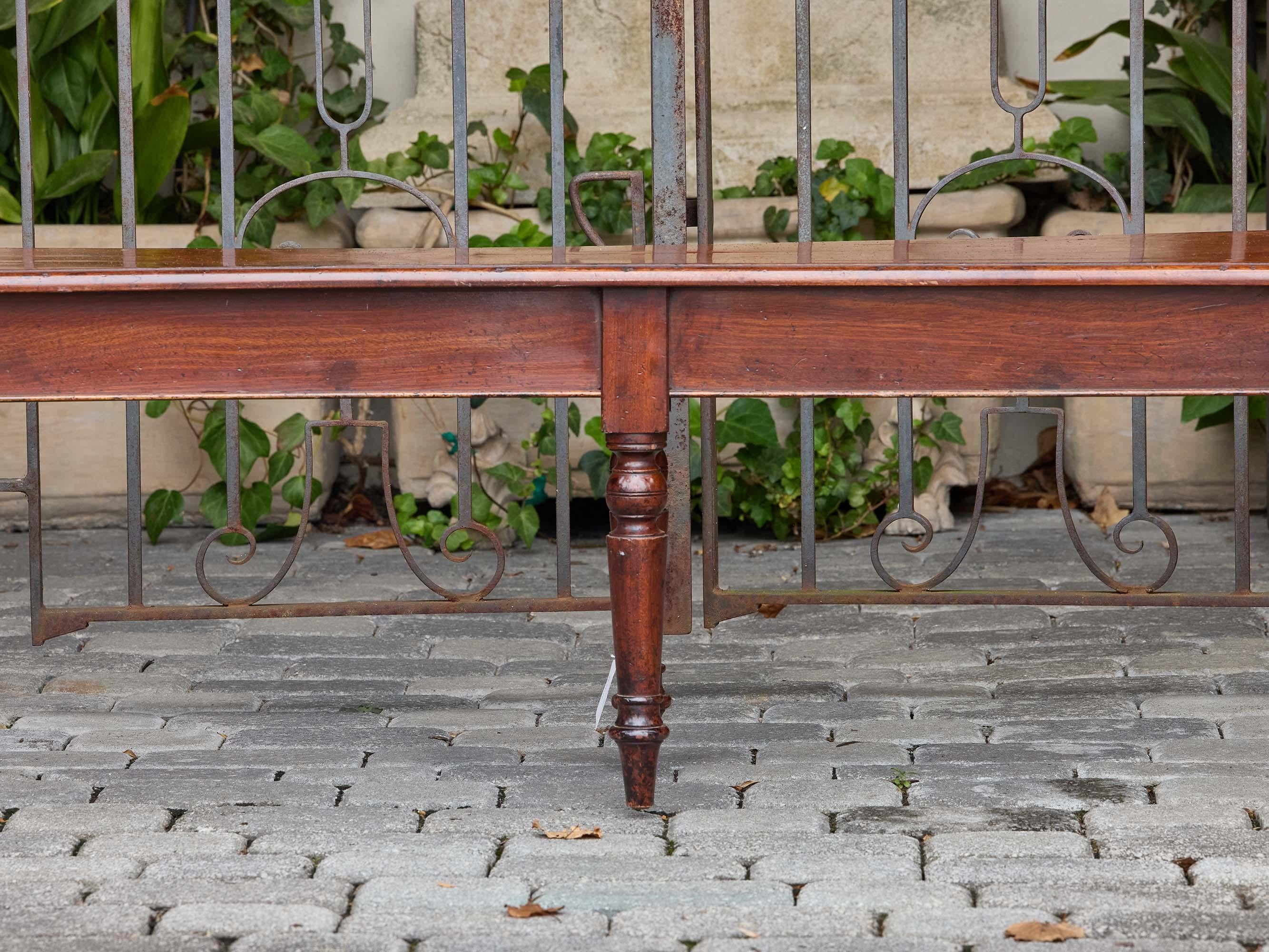An English mahogany bench from around 1940, blending traditional design with a long, elegant form. The rectangular seat is flanked at each end by scroll-shaped arm rests, lending a decorative flourish that contrasts with the otherwise streamlined