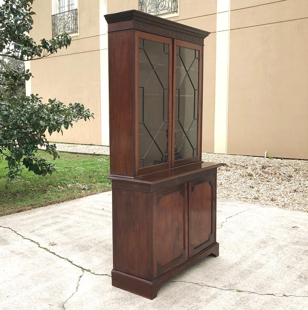 19th century English mahogany bookcase is a stately testament to pure and tailored architectural design, with a glazed upper tier for display and a bumped-out enclosed cabinet below for storage, all rendered in exceptional imported mahogany to last