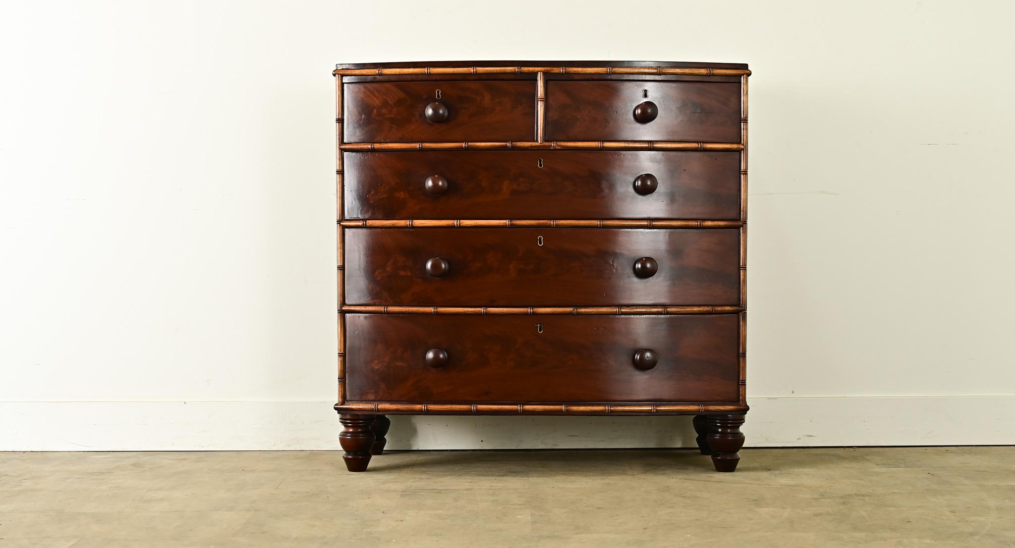 An English bow front chest made in the Regency period with faux bamboo detailing. Stunning mahogany glows with a rich coffee tone, framed by a bamboo-effect trim carved by hand to simulate nodes on every stalk. Each of the five drawers opens by
