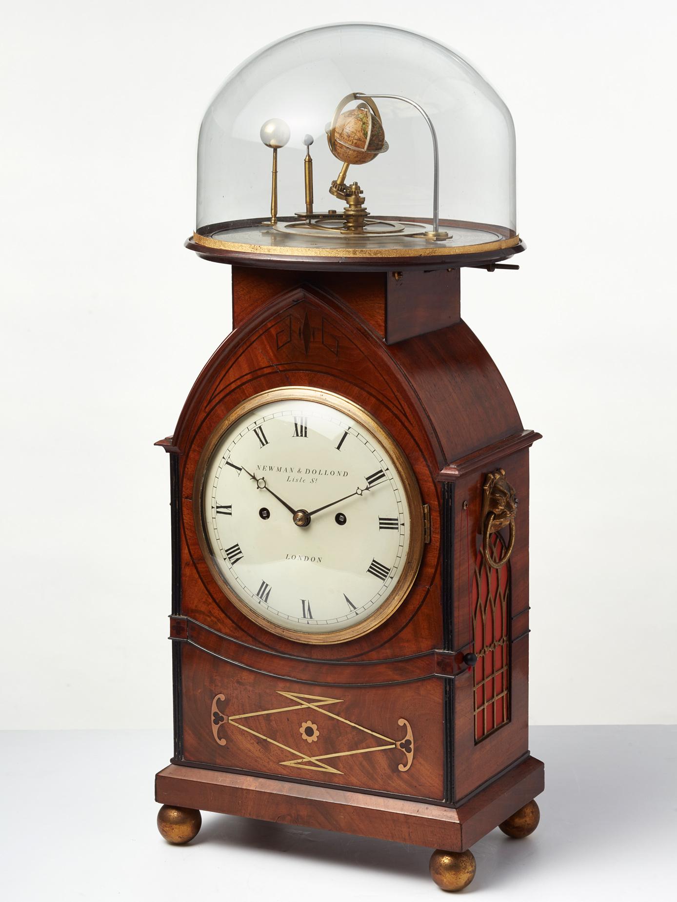 The beautiful Regency mahogany brass inlaid case on ball feet and on top the orrery connected to the movement. On the side, two bronze cast lion heads to handle the clock. On the right hand side, a pull repeat option. 

The eight day ‘on-bell’