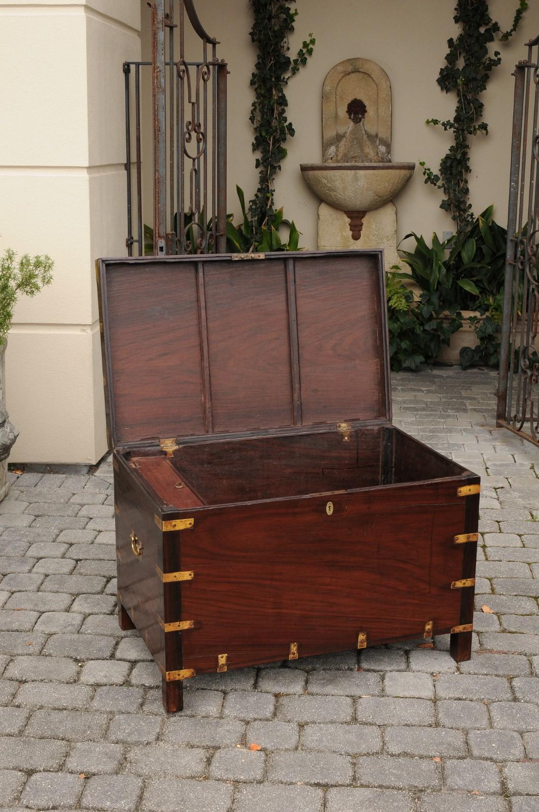 An English mahogany brass-bound Campaign trunk from the second half of the 19th century, with lateral handles. Born during the third quarter of the 19th century, this English Campaign trunk features a stylish linear mahogany structure, accentuated