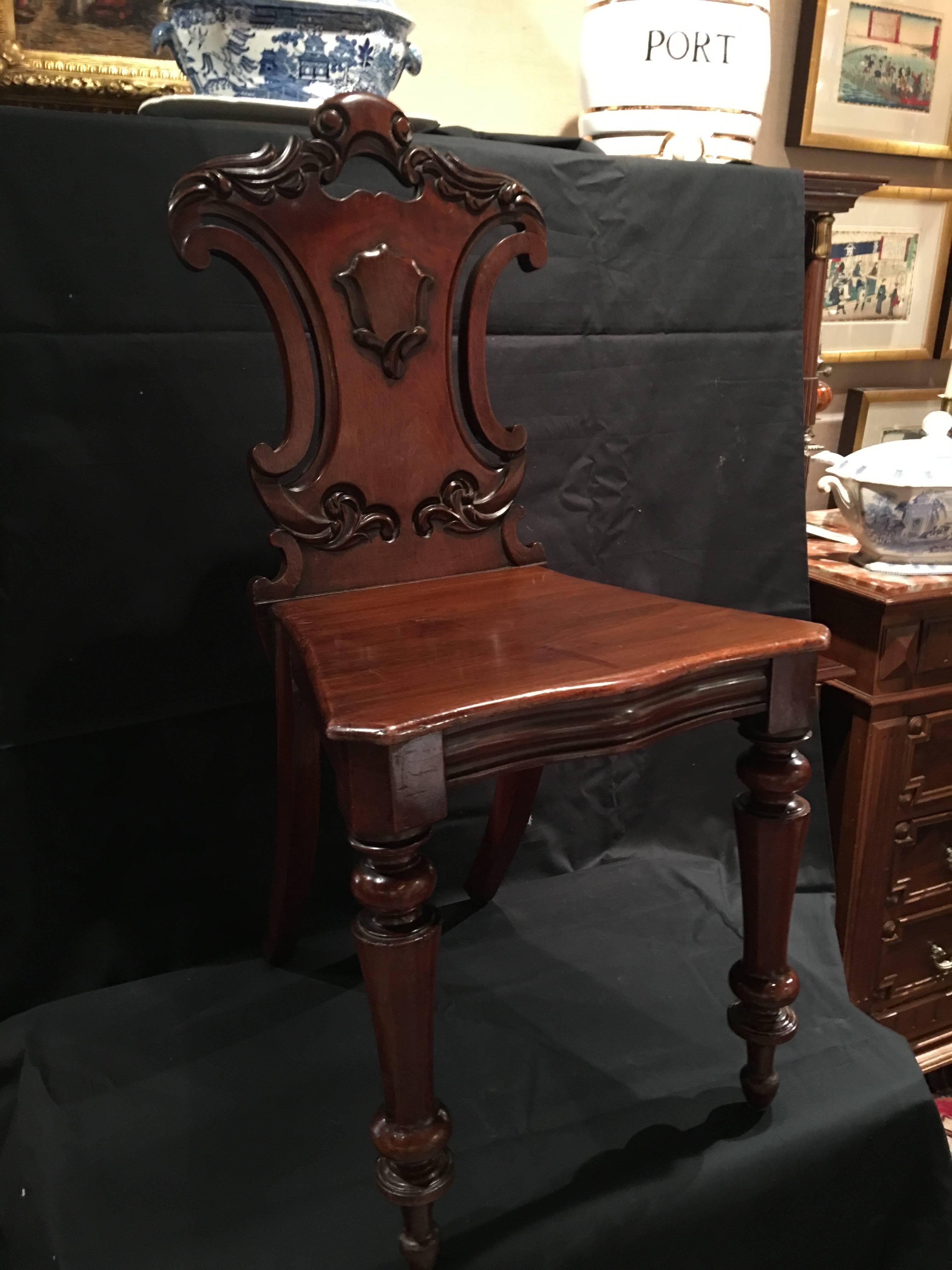 English mahogany carved pair of hall chairs, 19th century.