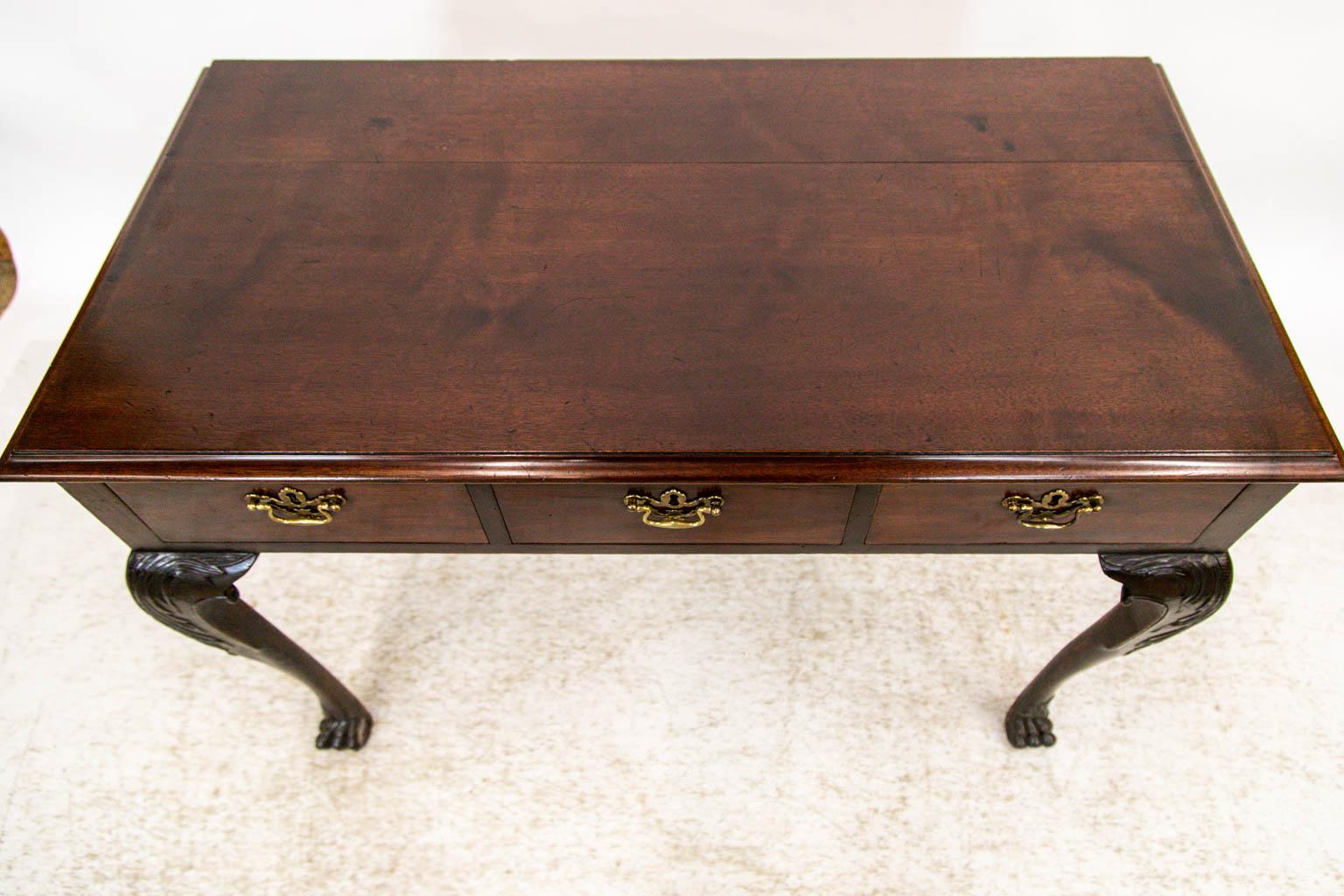 This three drawer Chippendale console table has carved legs with acanthus leaves and volutes and terminate in hairy paw feet.