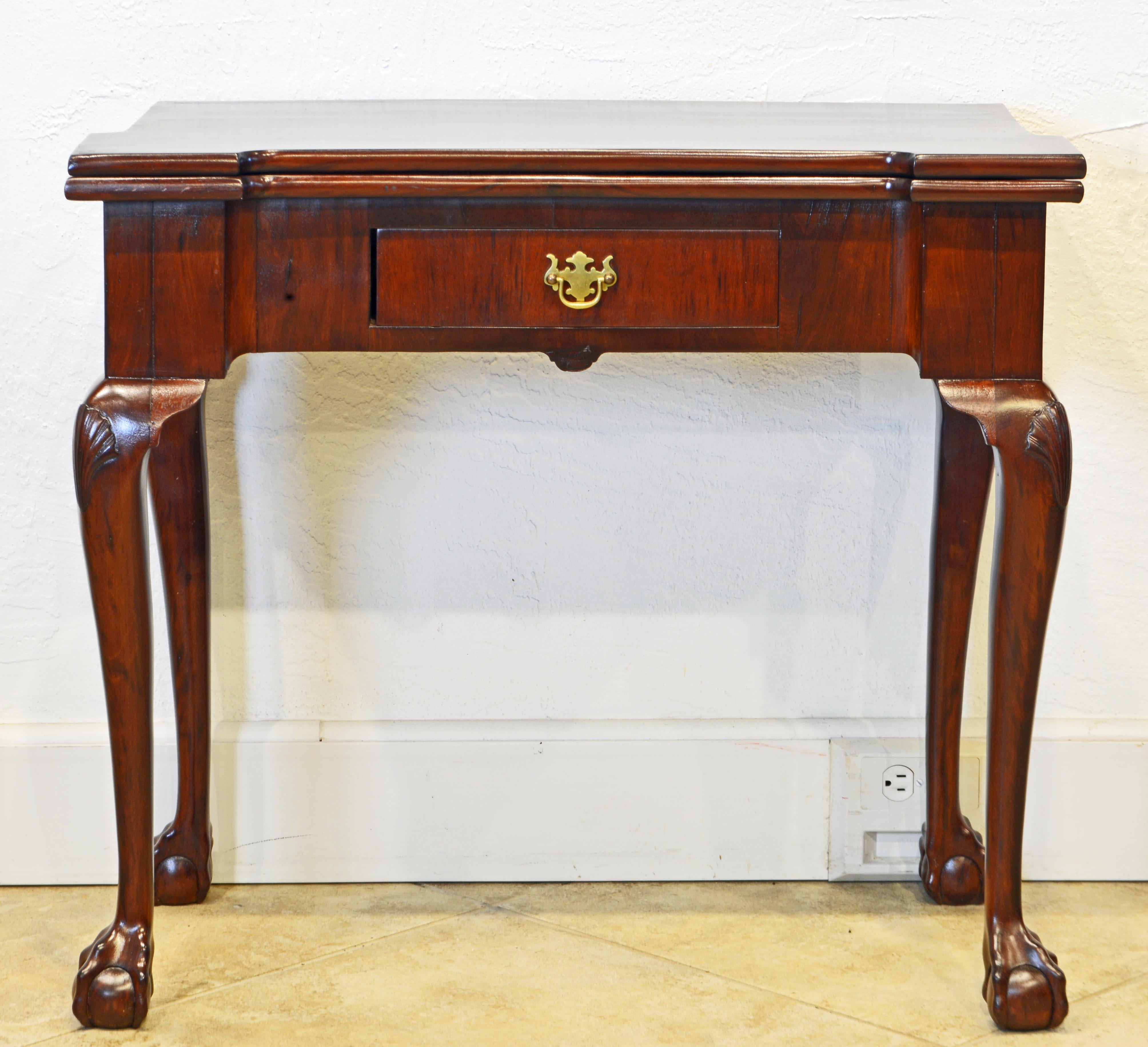 An excellent late 18th century Chippendale one drawer game table with shaped flip over top supported by swing back leg when open. The felt lined playing surface features four square corner dishes and four oval dishes. The table is raised on four