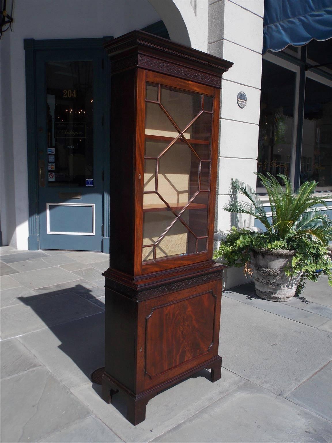 English mahogany Chippendale style diminutive bookcase with an upper case carved molded edge cornice, dental molding, intricately carved fret work, hinged glass door revealing two interior adjustable shelves, lower case carved molded edge, fret wok,