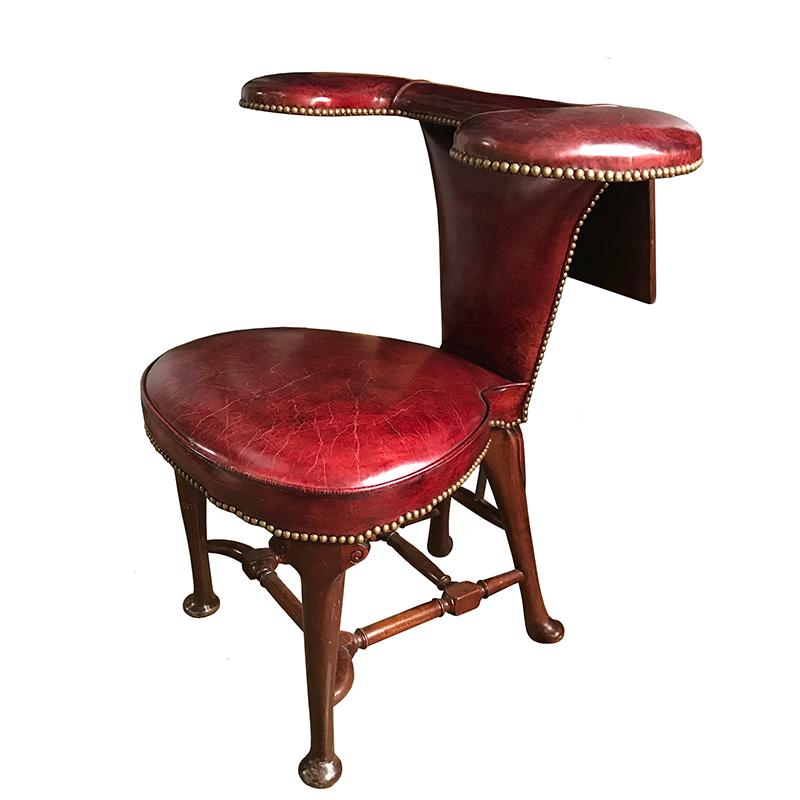 An English Edwardian studded leather cock fighting chair, or reading chair, in sumptuous dark red close-nailed leather with an adjustable writing/reading surface, sitting on pad feet with wonderfully turned stretchers. Maker's label reading 