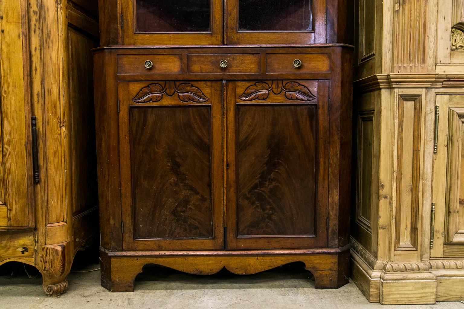 This English corner cupboard has the original wavy glass panes and the original locks. The upper and lower sections have shaped butterfly shelves. The upper section is painted red on the shelves and has red painted applied wallpaper. The upper and