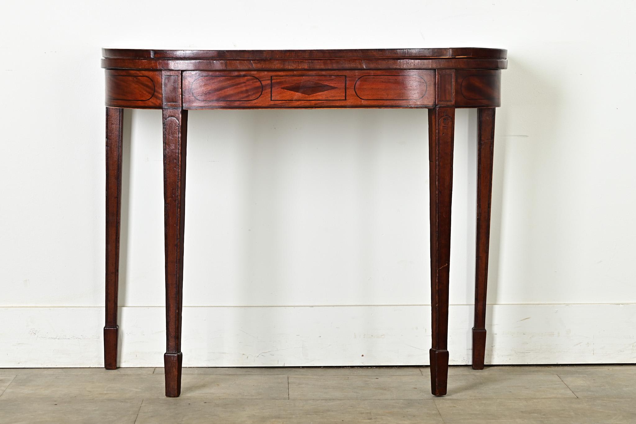 Made in England, this wonderful antique console table wins at being both a game table and a handsome demilune. If not in use and folded, the D-shaped console table sits firmly against a wall, showing off the apron with ebonized inlay over striated
